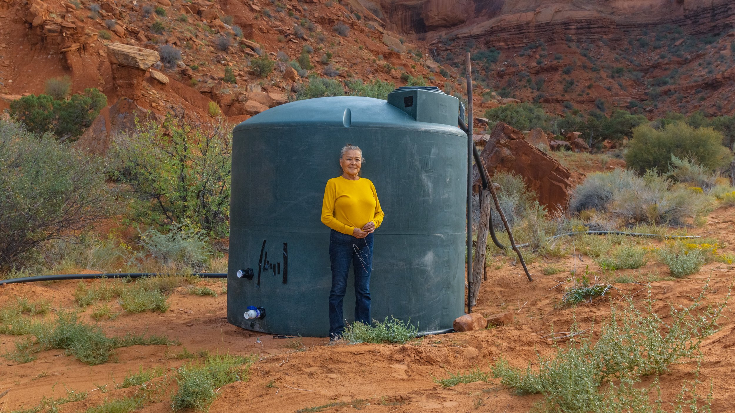  Effie Yazzie stands in front of one of the recently installed water collection tanks in Monument Valley called Piney Springs. Her grandfather used to collect water from the head of the spring when she was a little girl. This water collection tank is