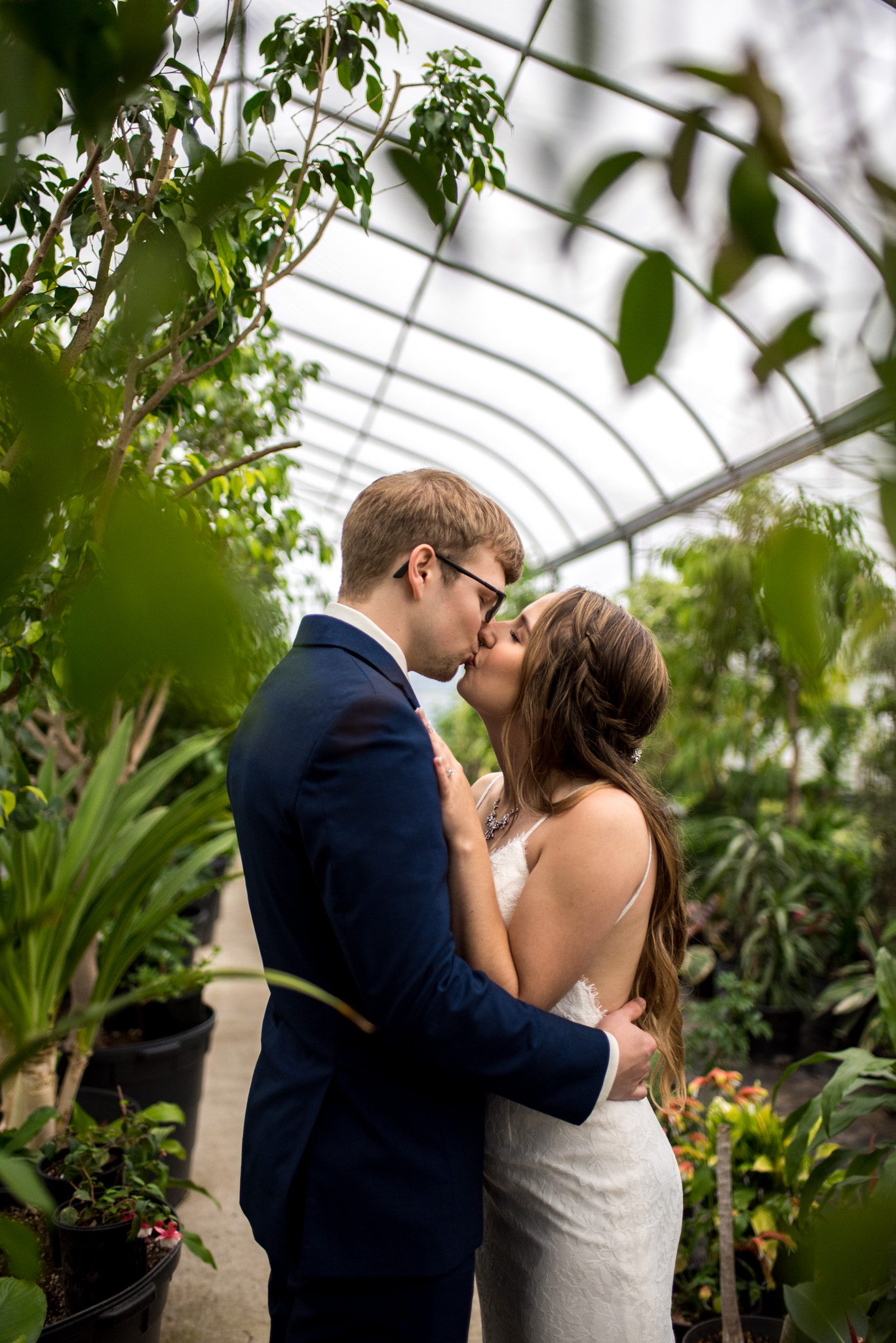 Bride and groom kissing in a greenhouse at Woodbridge Ponds