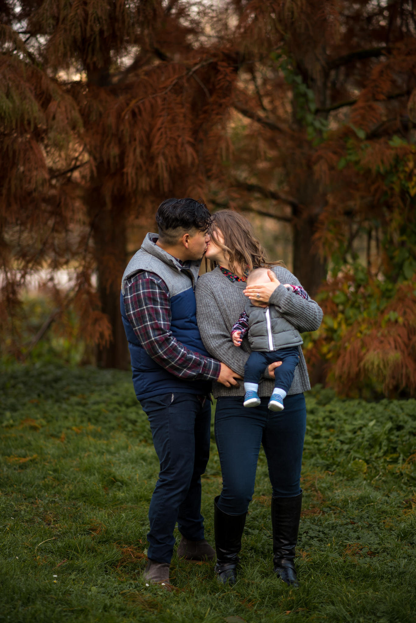 Cute couple kissing with their baby son in Queens Park, New Westminster BC