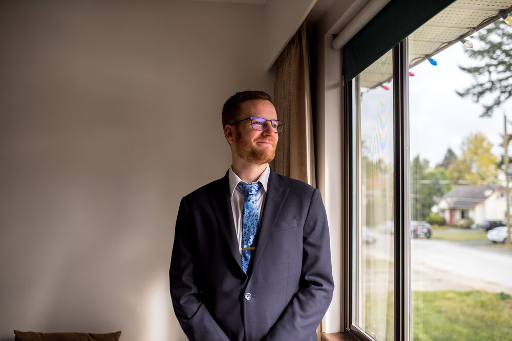 Groom looking out a window on his wedding day in Surrey, B.C.