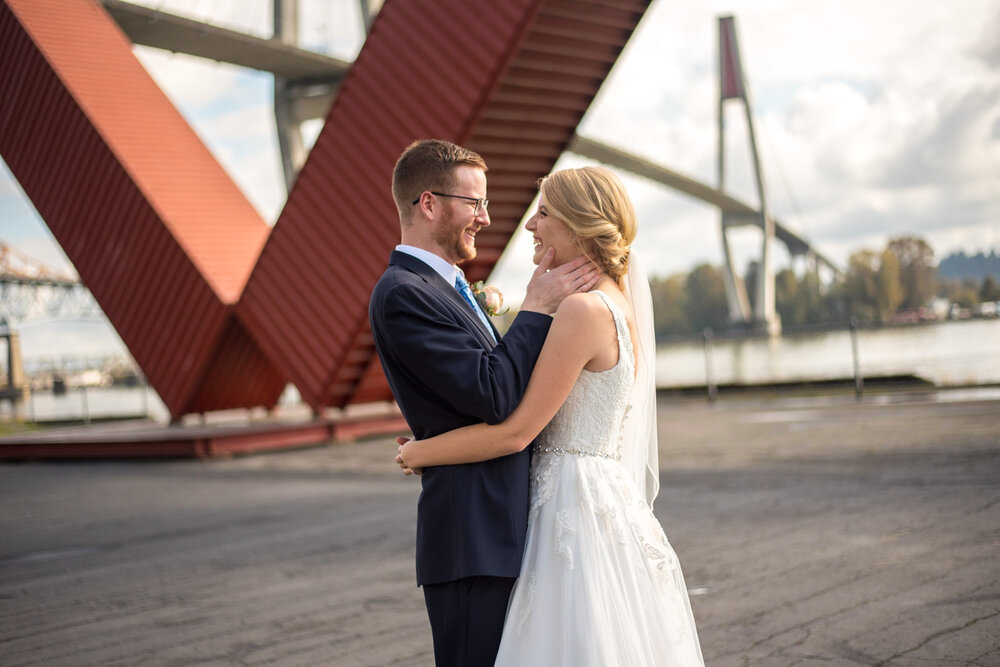 Groom holds bride's face in his hands during portrait time at Pier Park in New Westminster, B.C.