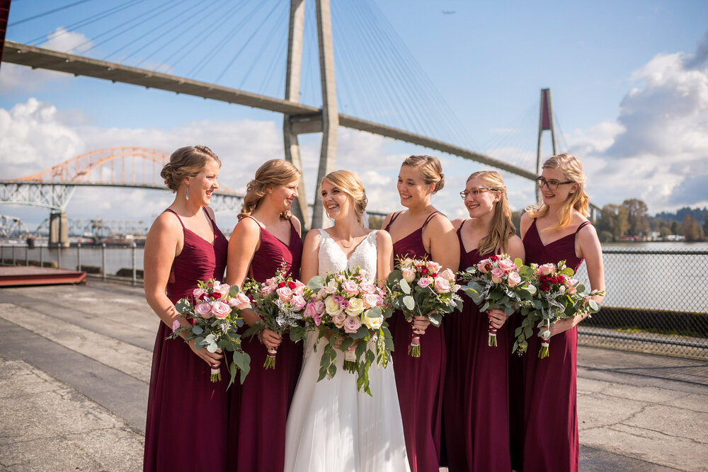 Bride and bridesmaids share a laugh with bridge view in the background