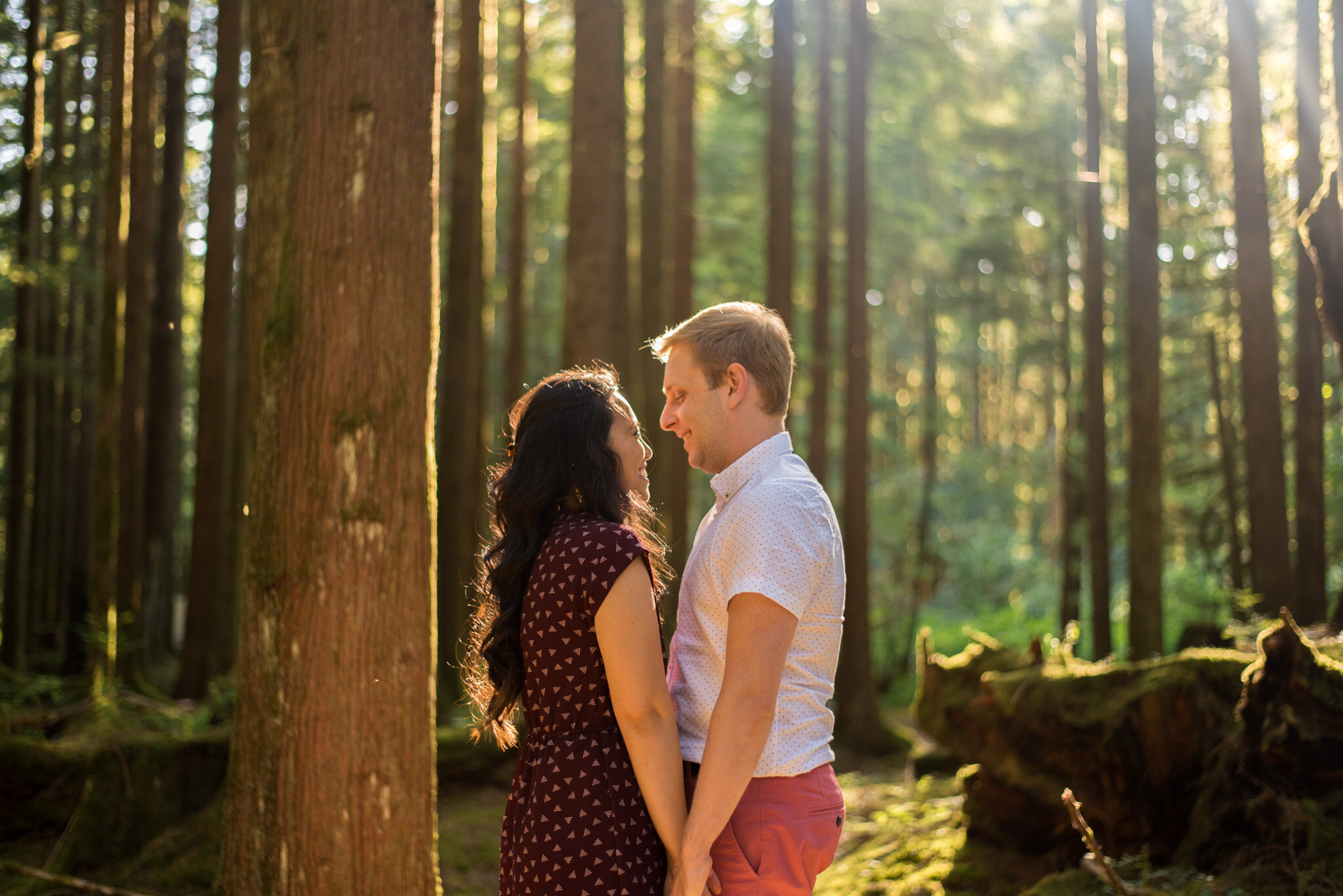 An engaged couple standing in the sunlight at Golden Ears Provincial Park in the forest