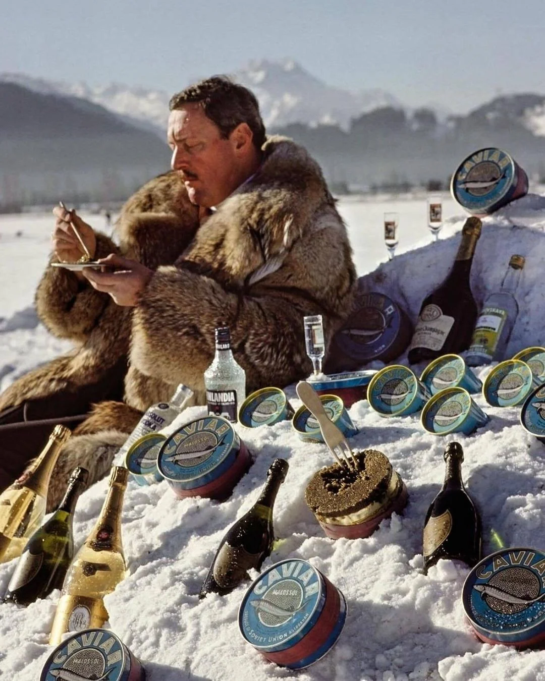 🔥 ☃️ GREAT TIMES. KAVIAR &amp; VODKA IN THE SNOW!

Tazi Glattfelder, wearing a fur coat, sits in the snow surrounded by caviar, vodka, and champagne, St. Moritz, Switzerland, 1989. The stube of @glattfelder.stmoritz is the place to be since 1931 in 