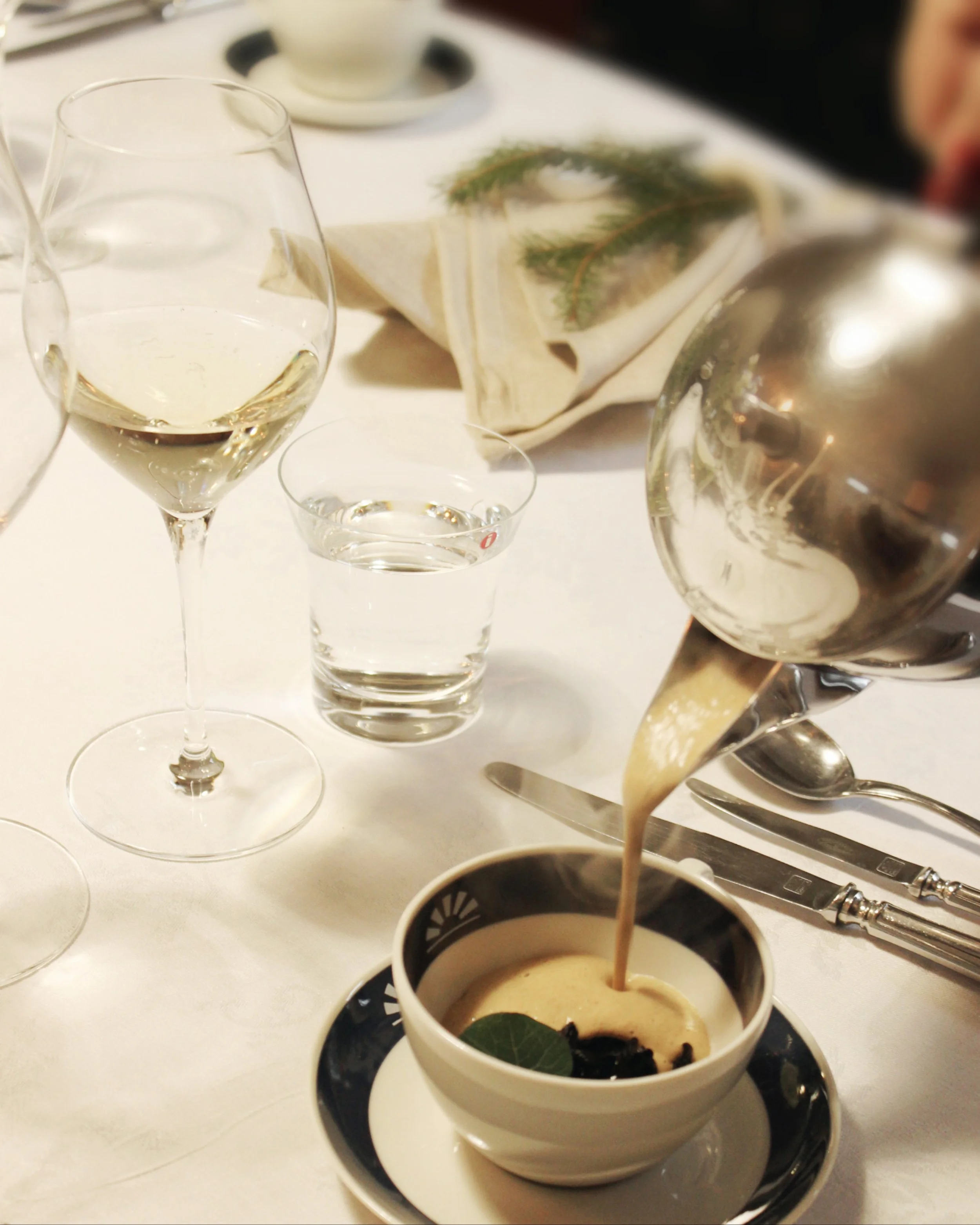 Kantolan tehtaanjohtajan illallinen, kattaus jossa tarjoilija parhaillaan kaataa alkukeittoa tarjoille lähikuvassa