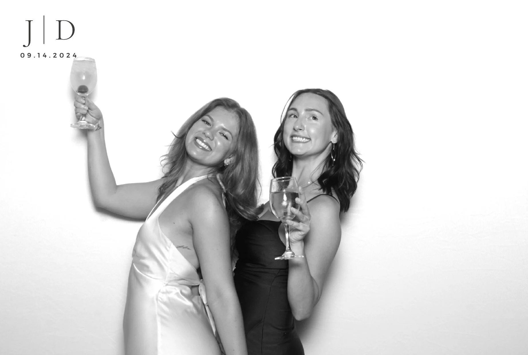Two women smiling and celebrating with wine glasses in black and white photo