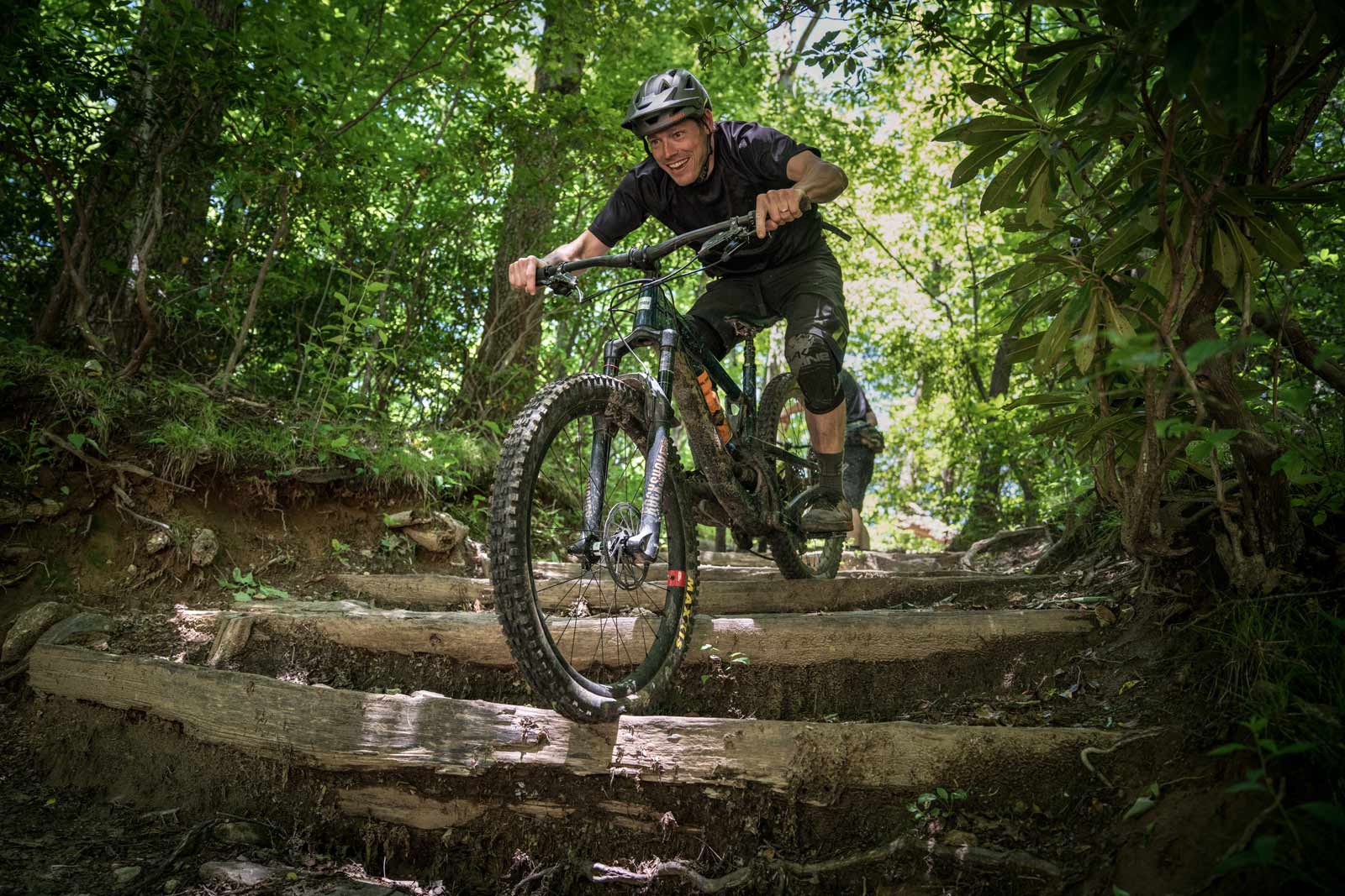 Mountain biker riding downhill over log steps at the Bike Farm (Copy)