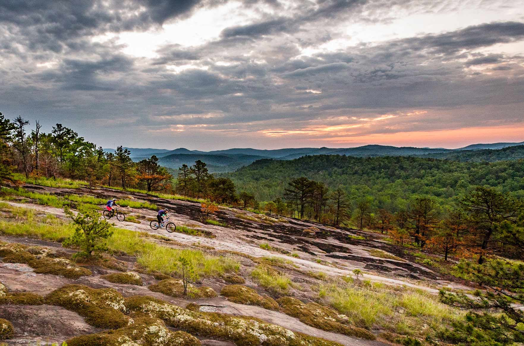 Tow mountain bikers riding over smooth rock terrain with a mountain view at the Bike Farm
