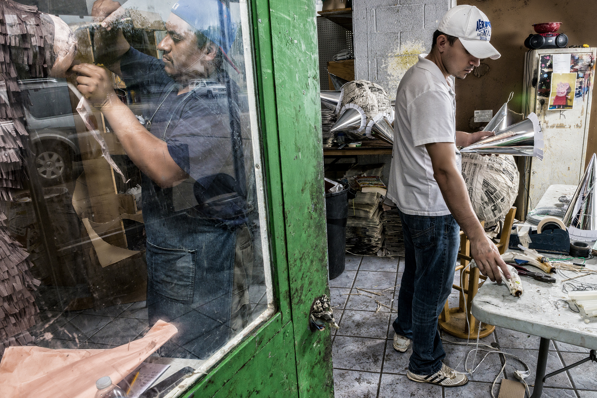  Piñatero Alex Santos and his assistant, Jesús Barradas, shape and refine piñatas at ABC Party in the Oak Cliff neighborhood in Dallas, TX.  Like Barradas, Santos was once an assistant and learned his craft by observing the shop’s previous piñatero, 