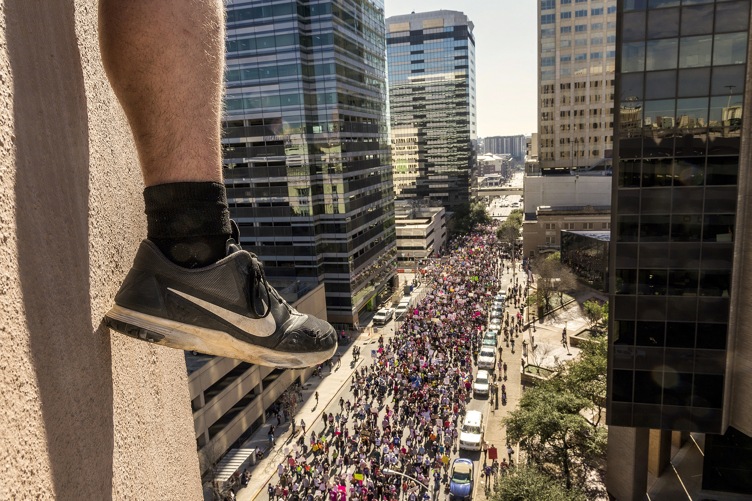  A man straddles the corner of a parking garage as an estimated 50,000 political protesters march toward the Texas State Capitol in Austin, TX on January 20, 2016, the day Donald Trump was inaugurated President of the United States.  Similar protests