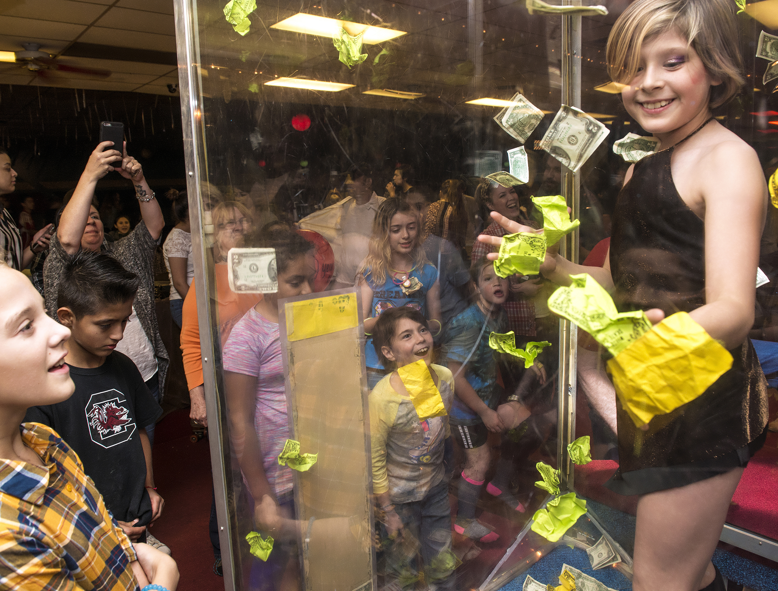  A girl attempts to snag bills in the money booth at White Rock Skate’s last hoorah in the Lake Highlands neighborhood in Dallas, TX.  Built in 1973, White Rock Skate became a local institution for generations of fun-loving, rollerskating children an