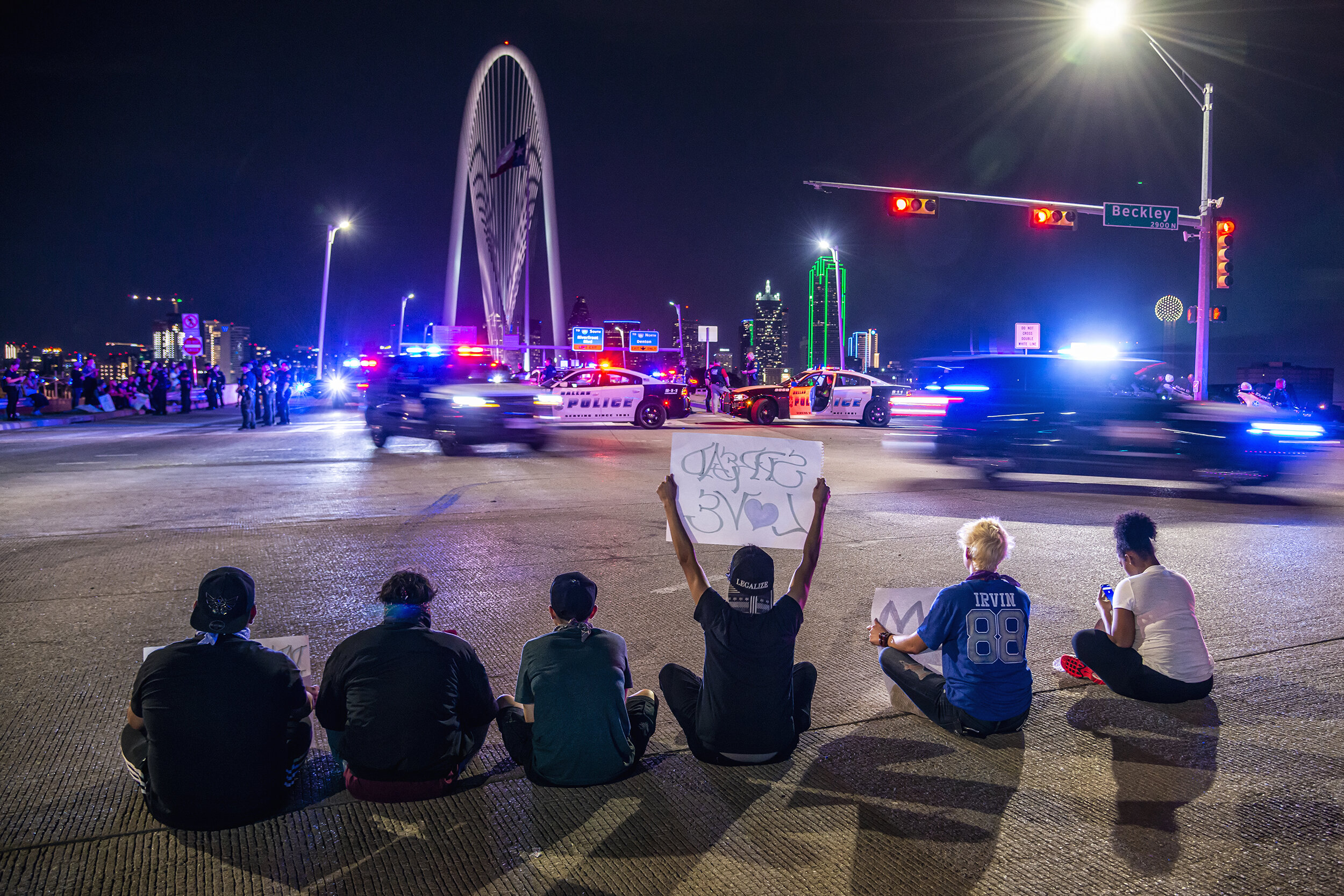  A protester holds up a sign reading “spread love” as police withdraw from the Margaret Hunt Hill Bridge in Dallas, TX on June 1, 2020.  After trapping and detaining over 700 protesters on the bridge in a massive kettling maneuver, the protesters wer