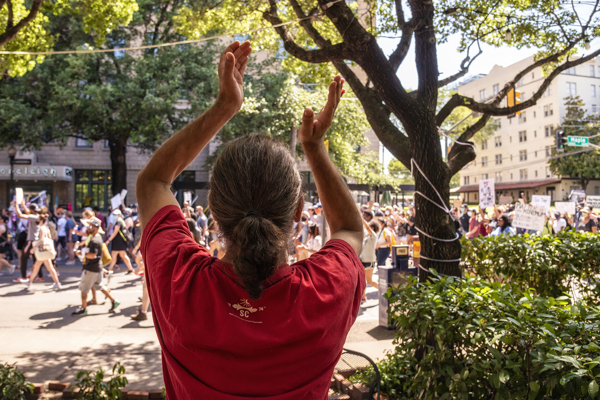  A bar patron applauds protesters marching down Maple Avenue in uptown Dallas, TX on June 13, 2020.  Throughout the month’s protests, motorists and residents routinely honked their horns or banged pots with kitchen utensils to show support. 