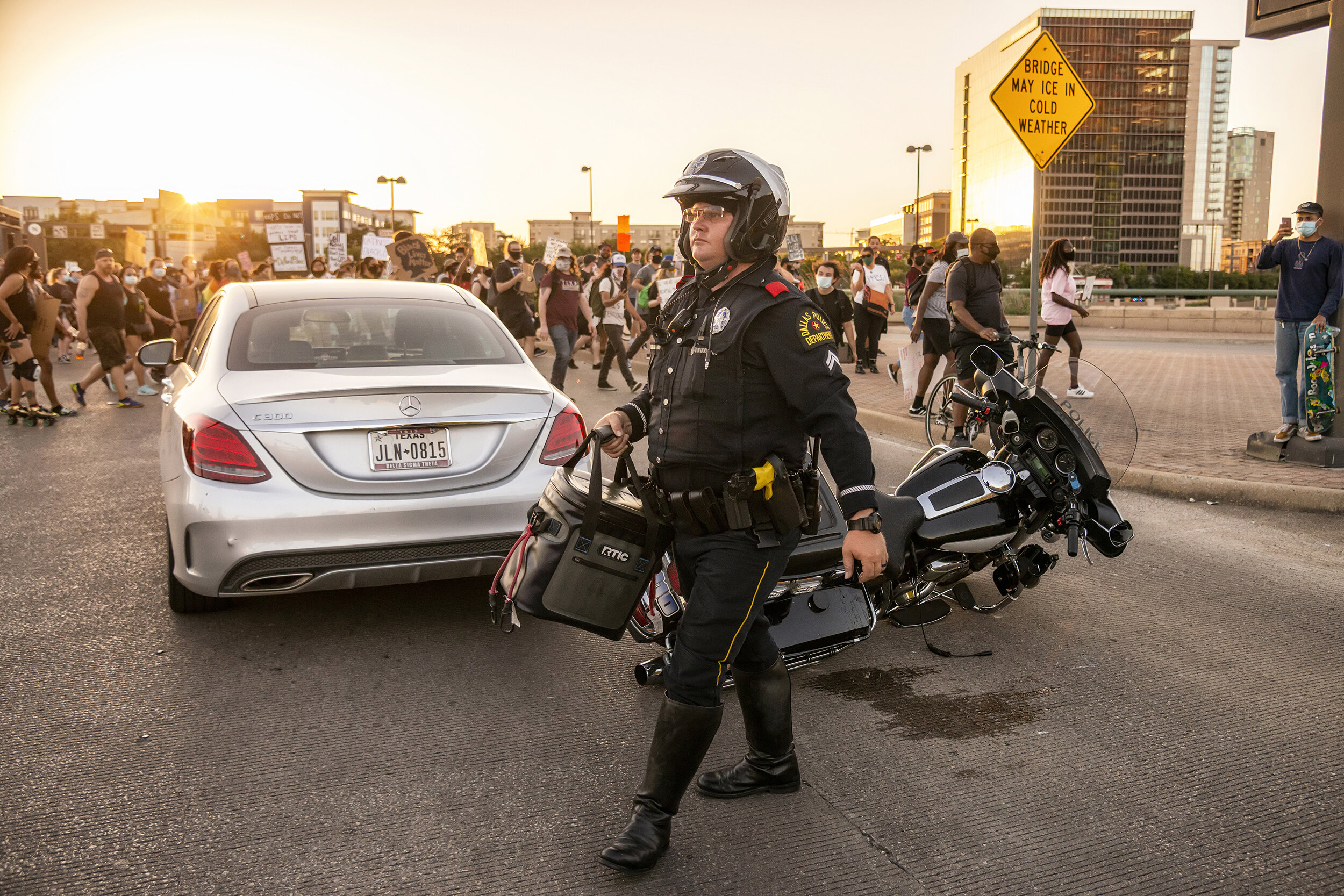  A Dallas police officer carries a cooler after a motorist crashed into a police motorcycle during the Ride for Justice protest in Dallas, TX on June 13, 2020.  Cyclists, skaters, rollerbladers and skateboarders rolled ahead of a pedestrian protest t