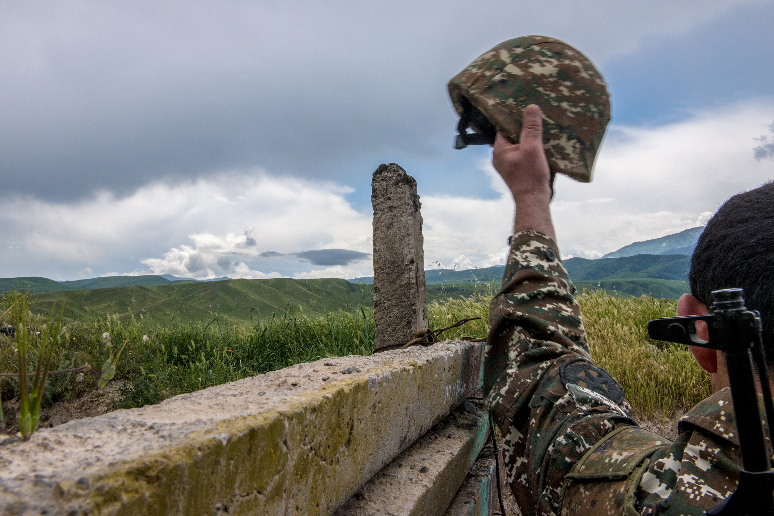  An NKR soldier lifts his helmet while facing a disputed landscape.  Estimates put the total number of troops facing off on the Line of Contact at 40,000, making the NKR-Azerbaijan border among the most militarized in the world. 