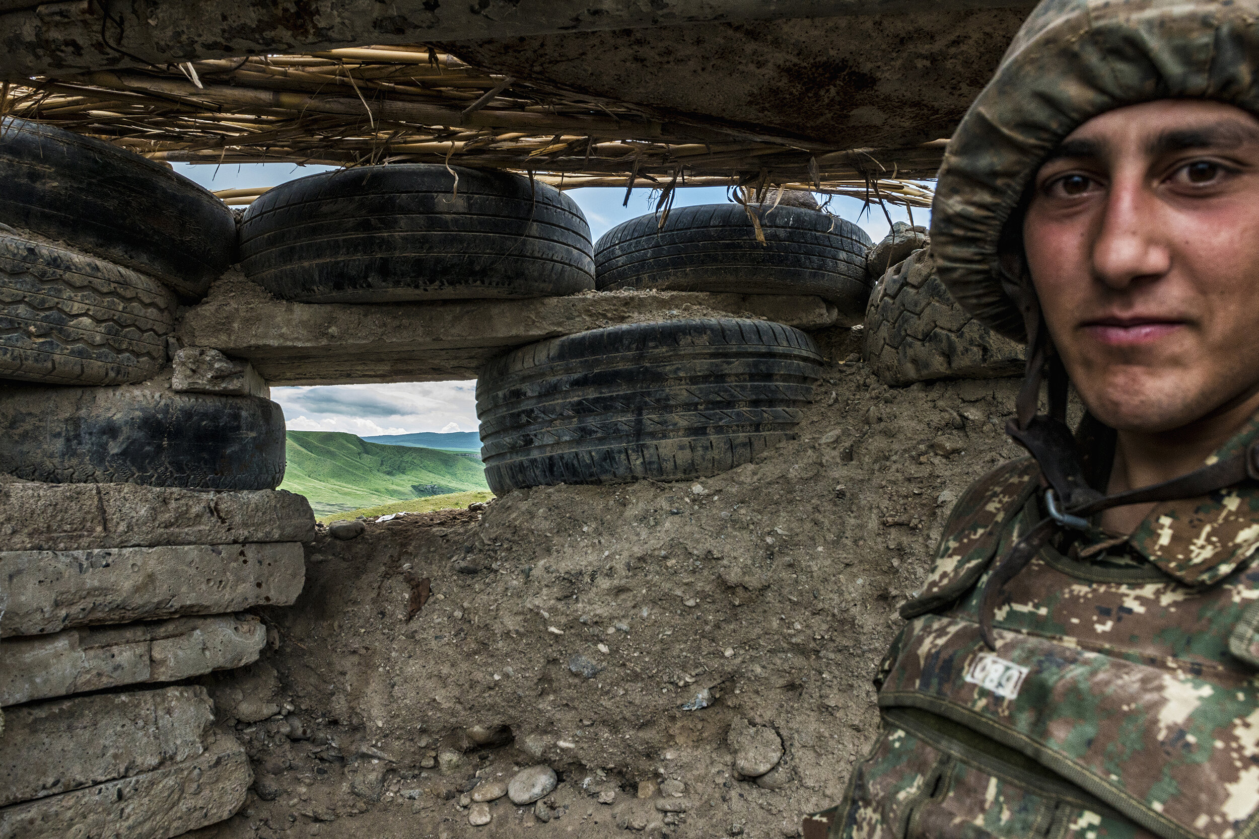  An NKR machine gunner mans a firing position on the Line of Contact in Nagorno-Karabakh.  Perimeter defenses like old tires and tin cans strung in barbed wire were prevalent throughout the trench system with fortifications and mines filling the no m