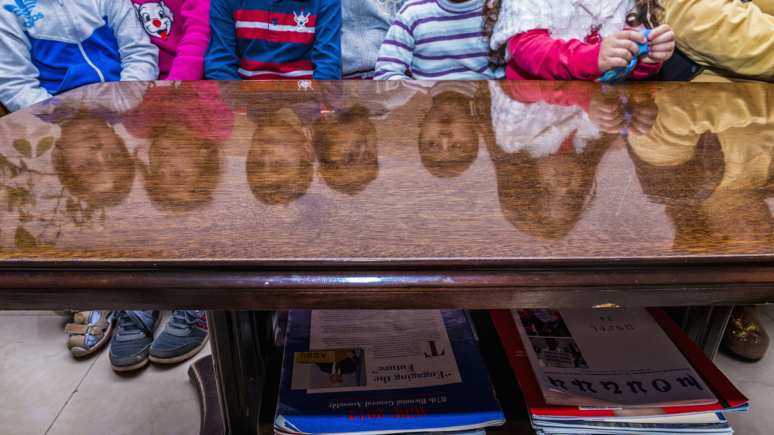  Children displaced by the Four-Day War are reflected in a table at the Nairi Hotel in Stepanakert, Nagorno-Karabakh.  Thousands of women and children fled towns along the Line of Contact while men stayed to defend and rebuild their homes. 