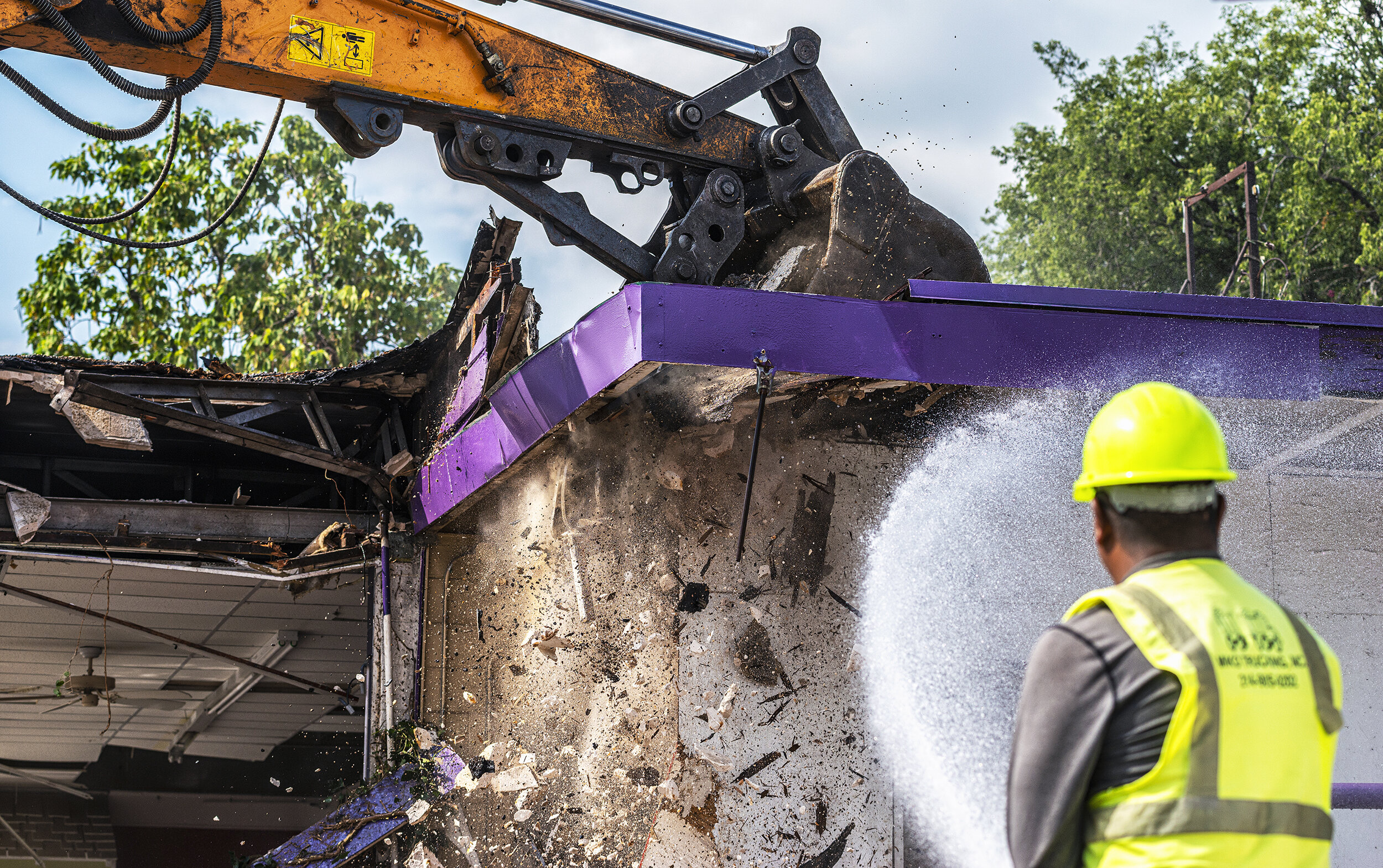  While an excavator’s bucket crashes through a roof, a demolition worker hoses down the dust of a mid-century modern building that once housed Joyce Florist in the Oak Cliff neighborhood of Dallas, TX.  Owners demolished the 1950s building, which the