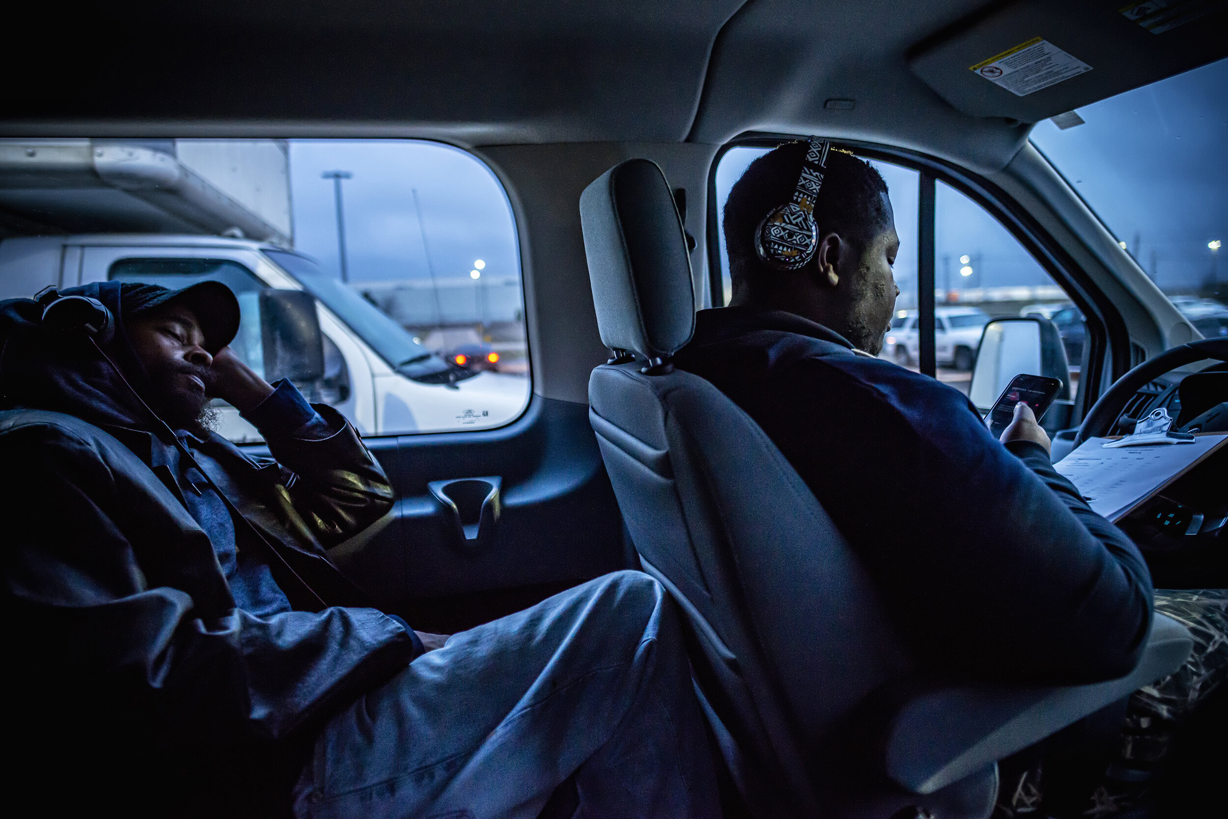  Demarcus Corbins phones a fare while a factory worker sleeps after his night shift at a Sterlite plastic factory in Ennis, TX.  Corbins worked with his father, Curtis Corbins, who started the nonprofit Southern Dallas Link. With shortfalls in public