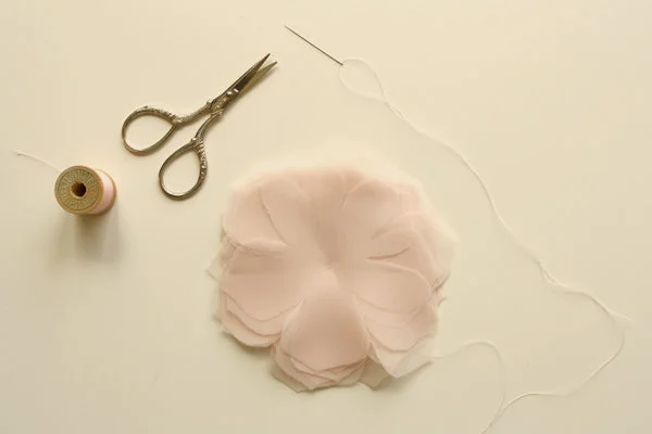 Image of a needle and thread, a flower and staggering petals