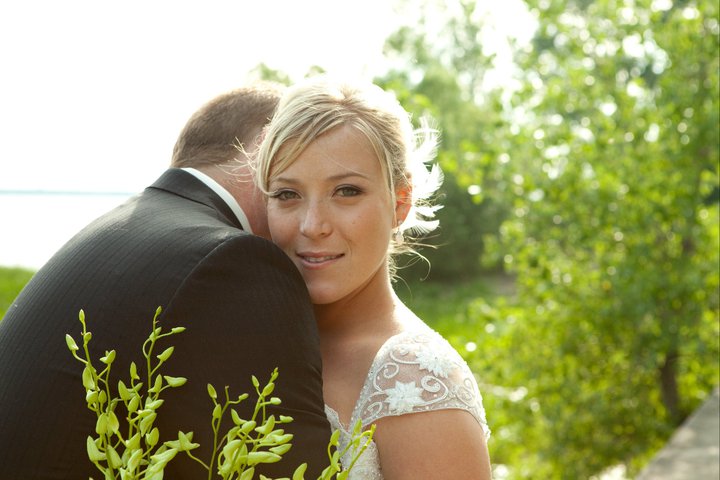 Woman in wedding dress hugging her husband looking at the camera