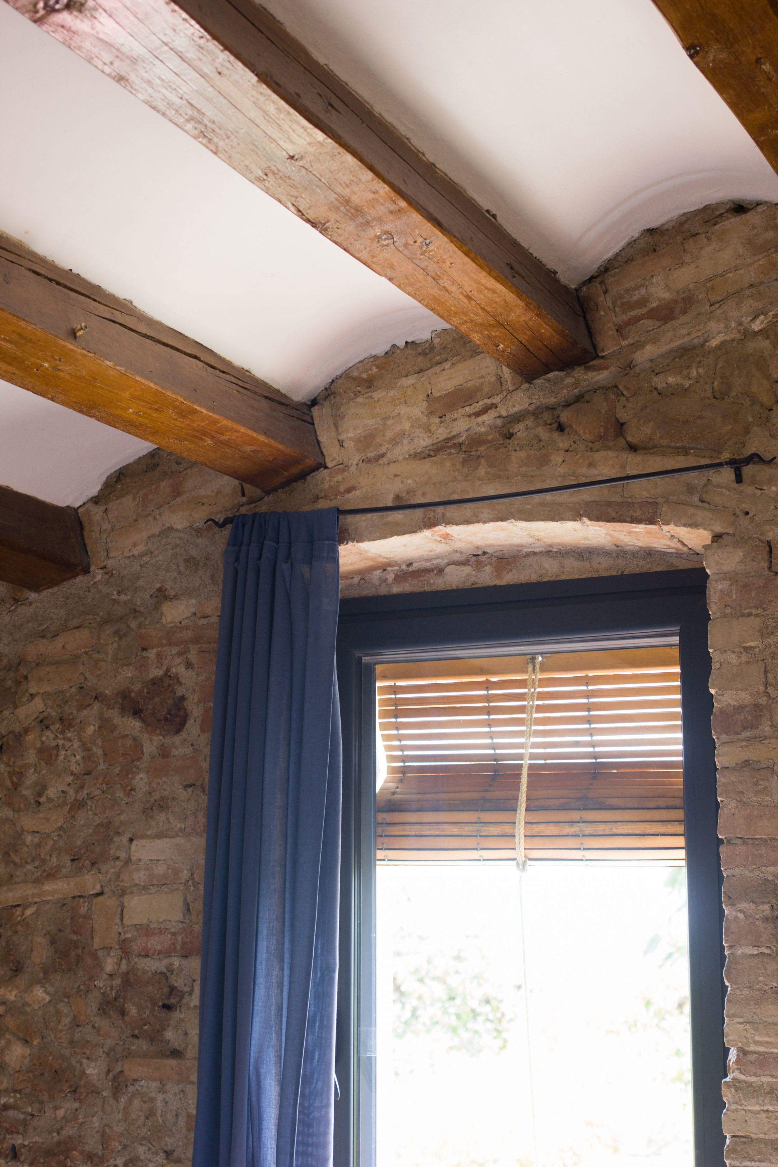 Wooden beam ceiling interior design with blinds on the curved window