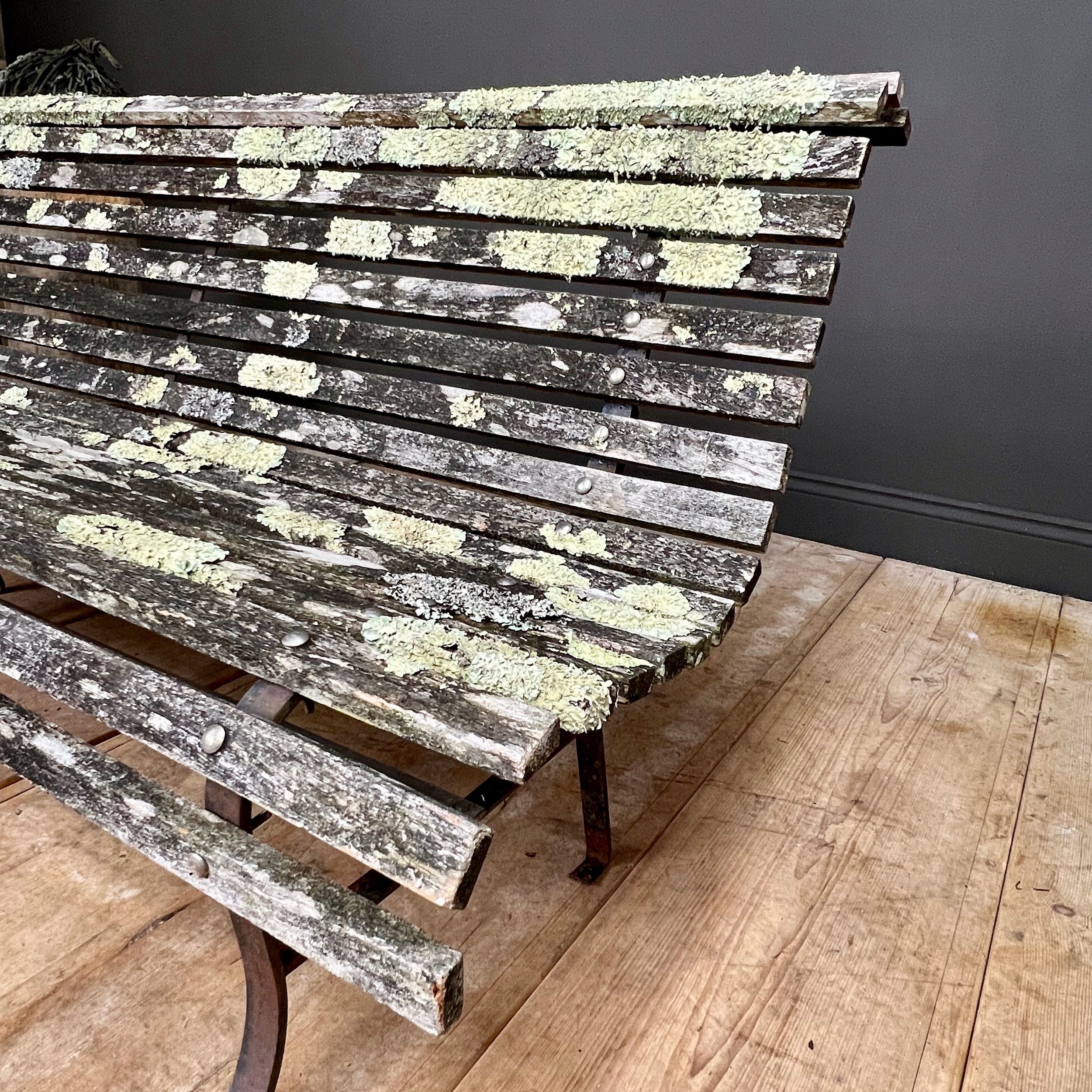 Fine example of a period scrolling garden bench wonderfully camouflaged with forest lichen