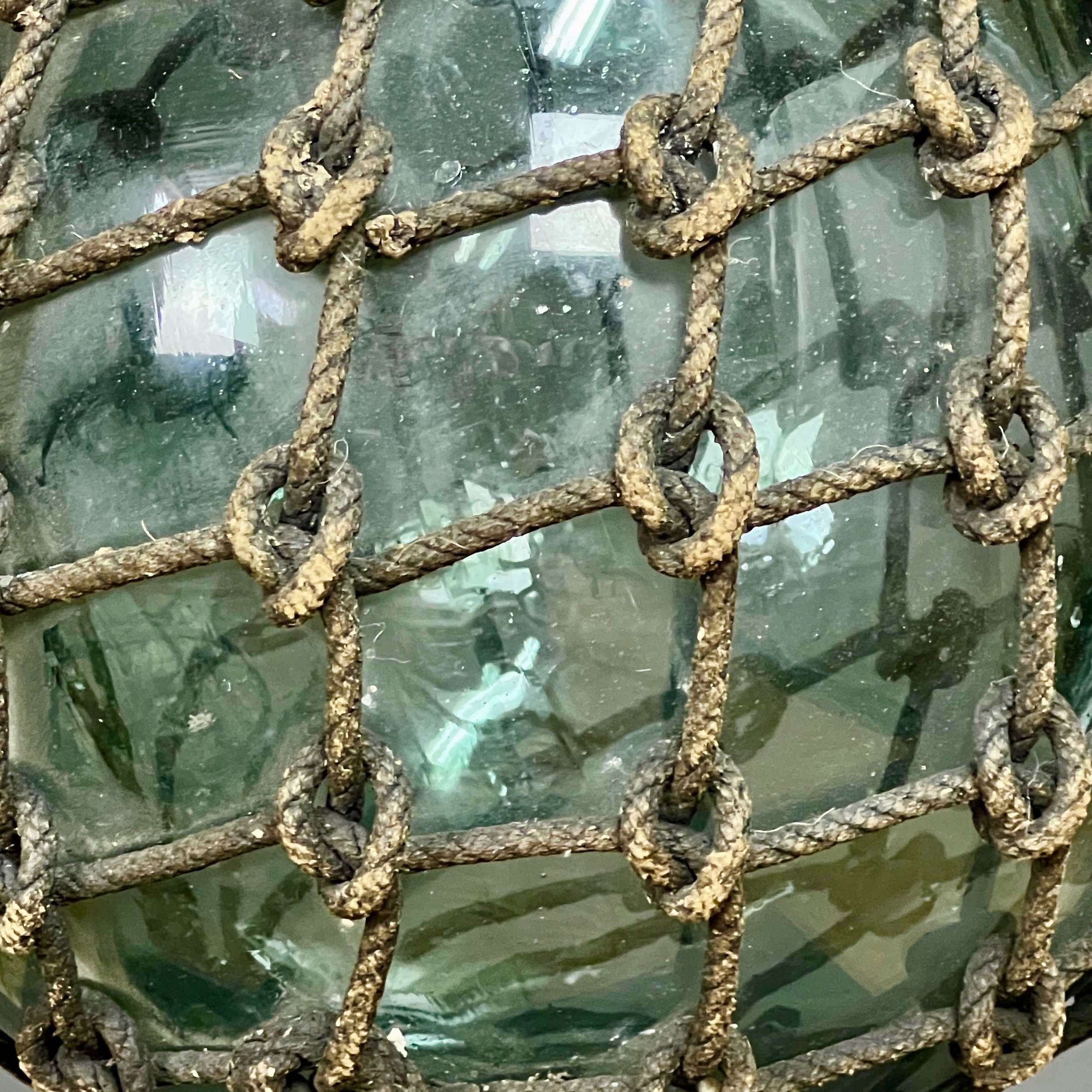 Pair of large glass and rope fishing buoys.