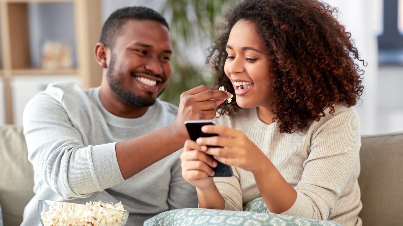 Black couple sitting together sharing a phone — couples therapy in Katy TX