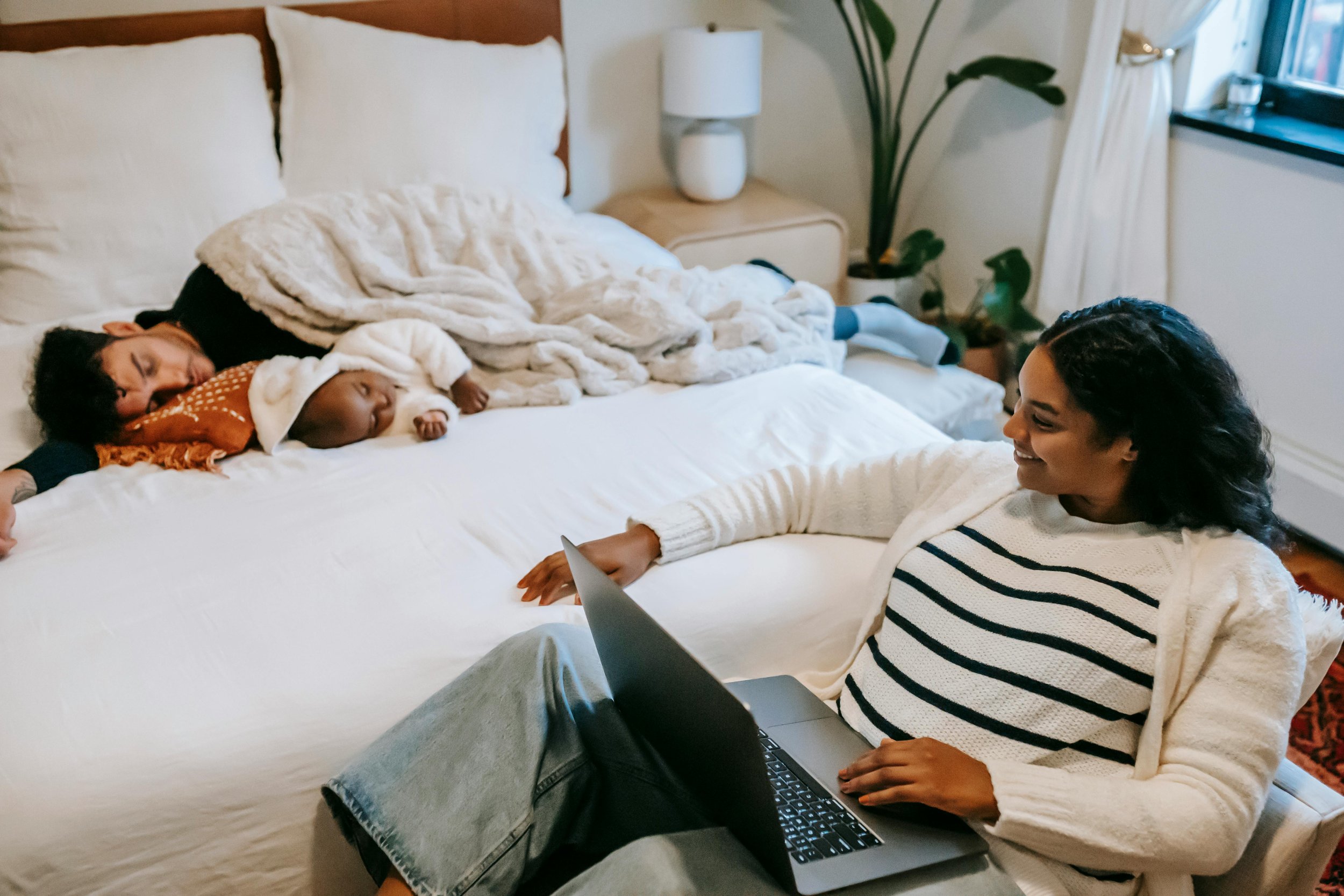 Black mother with sleeping baby and laptop — co-parenting therapy telehealth Texas
