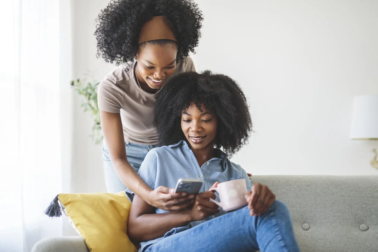 Black mother and teenage daughter sitting together on a couch — teen parenting therapy in Houston TX
