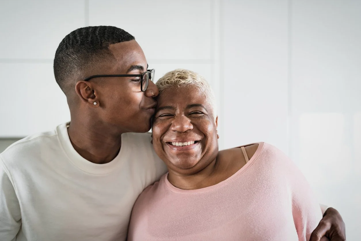 Black teenager kissing laughing mom on the cheek — teen parenting therapy in Houston TX