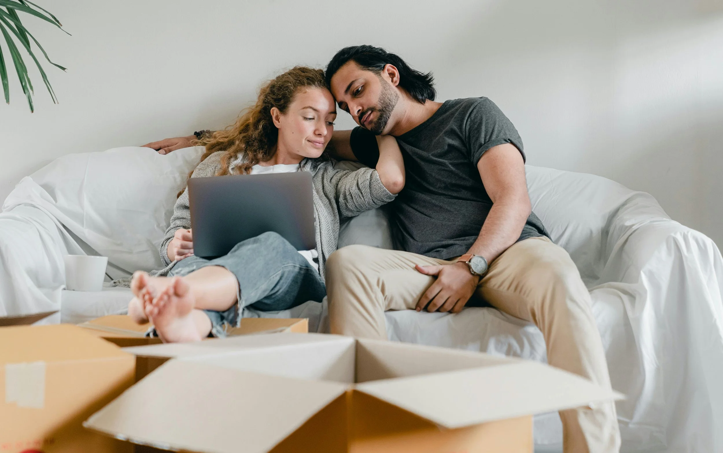 Couple sitting on a couch with a laptop during a virtual premarital coaching session with Ra'Shunda and Jason Adams