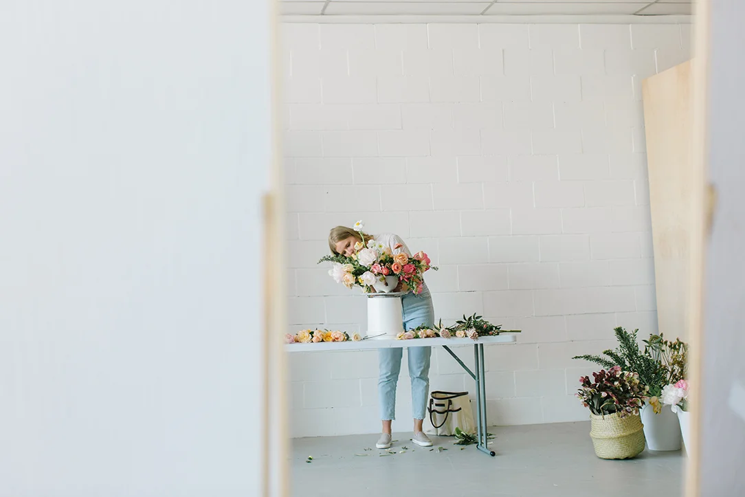 florist arranging flowers on table reflected through mirror in white rentable studio in danville ca.jpg