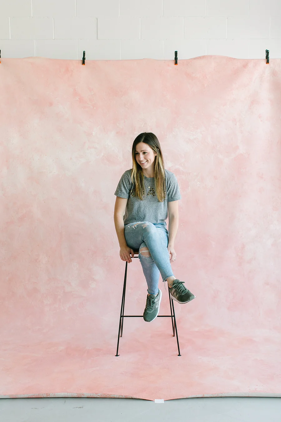 painter sitting on wooden stool in front of pink custom painted backdrop in natural light studio in dublin ca.jpg