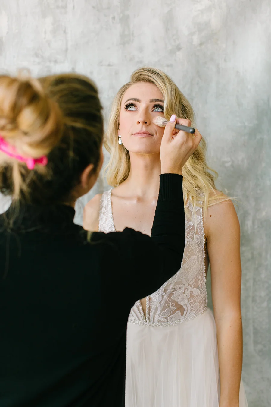 makeup artist applying makeup on model in front of grey custom painted backdrop in rentable white studio in danville ca.jpg