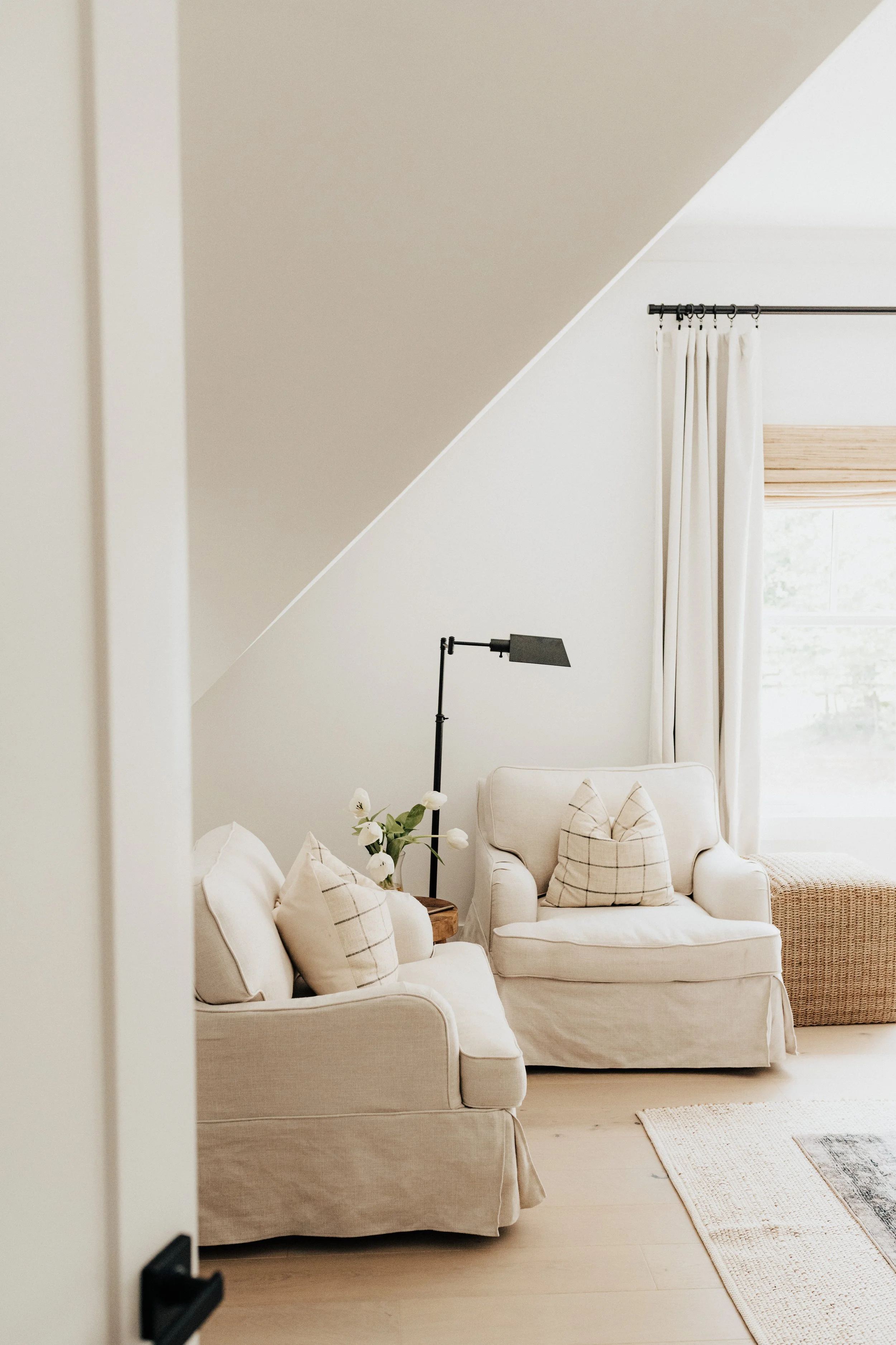 bedroom seating area with cream neutral couches and black lamp