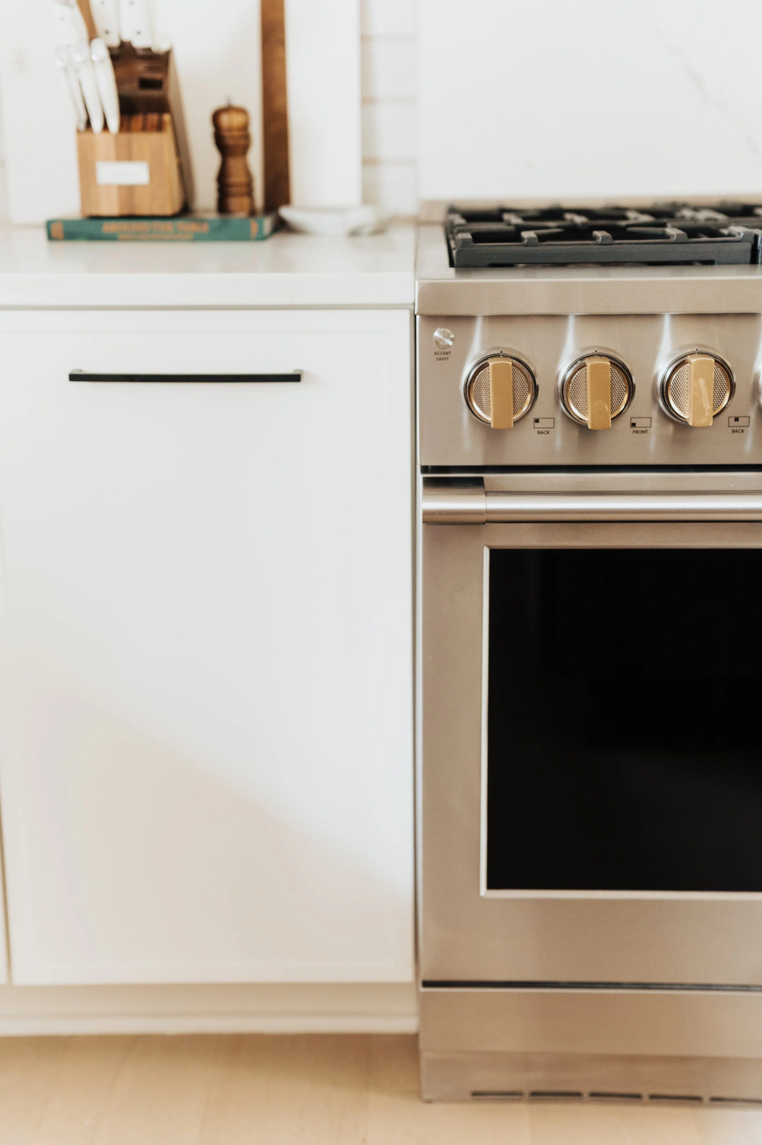 monogram stove with gold knobs and white cabinets