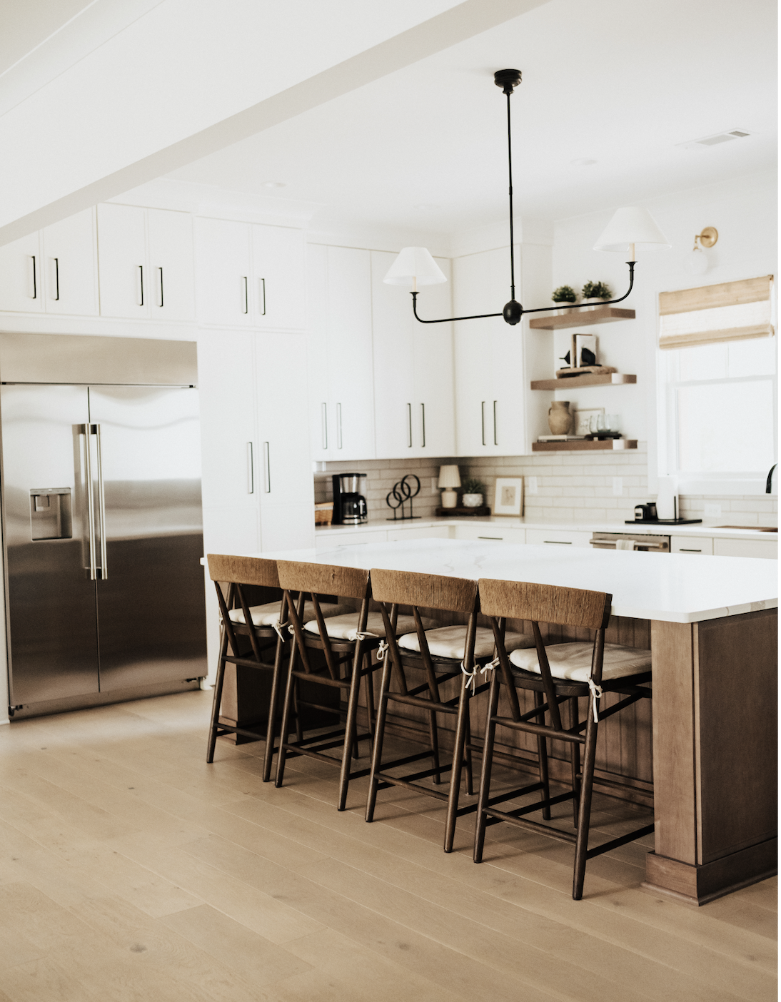 white kitchen with cabinets and large island and wooden chairs