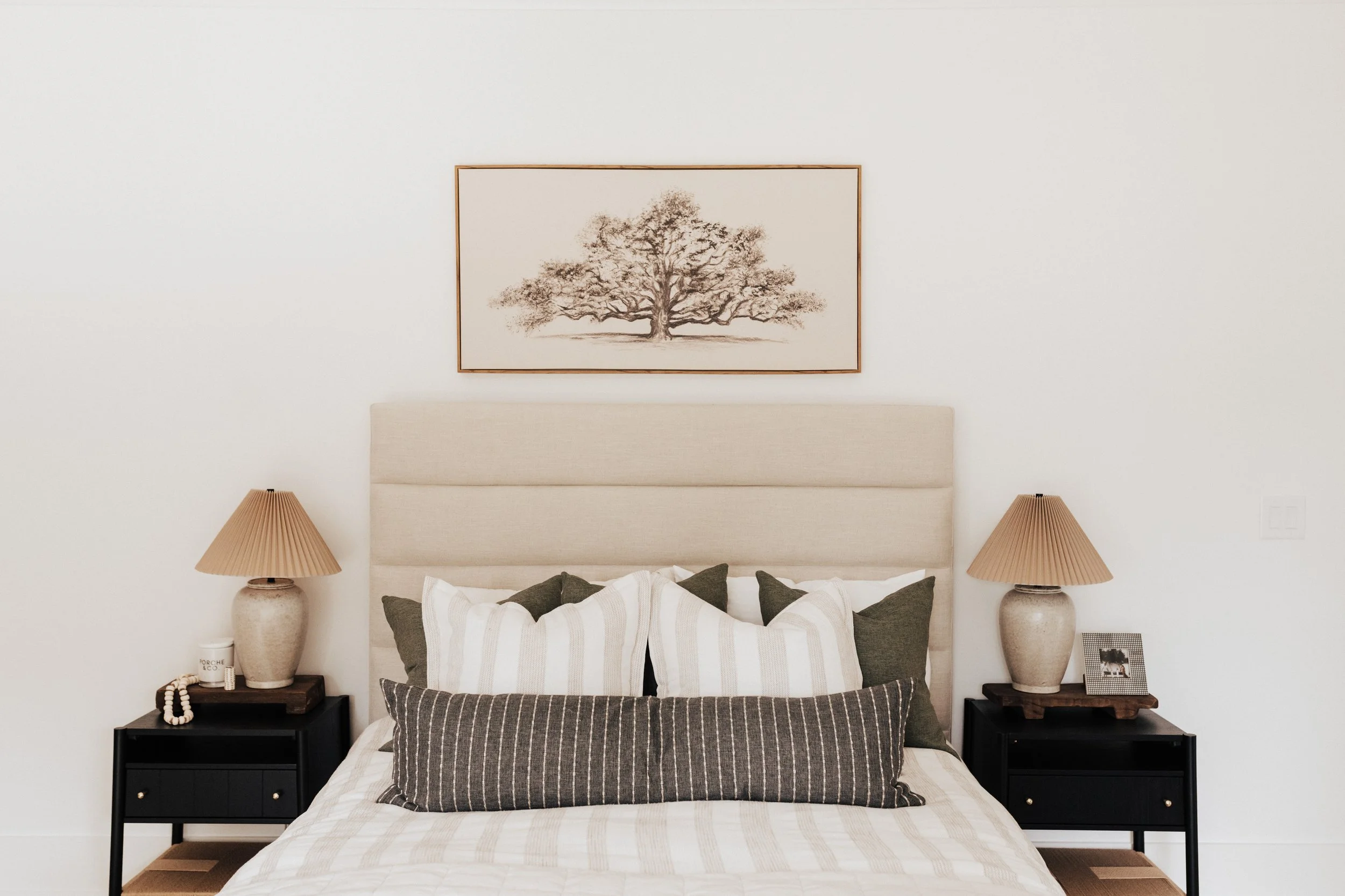 guestroom bed with tree photo as the focal point and black nightstands with tan lamps