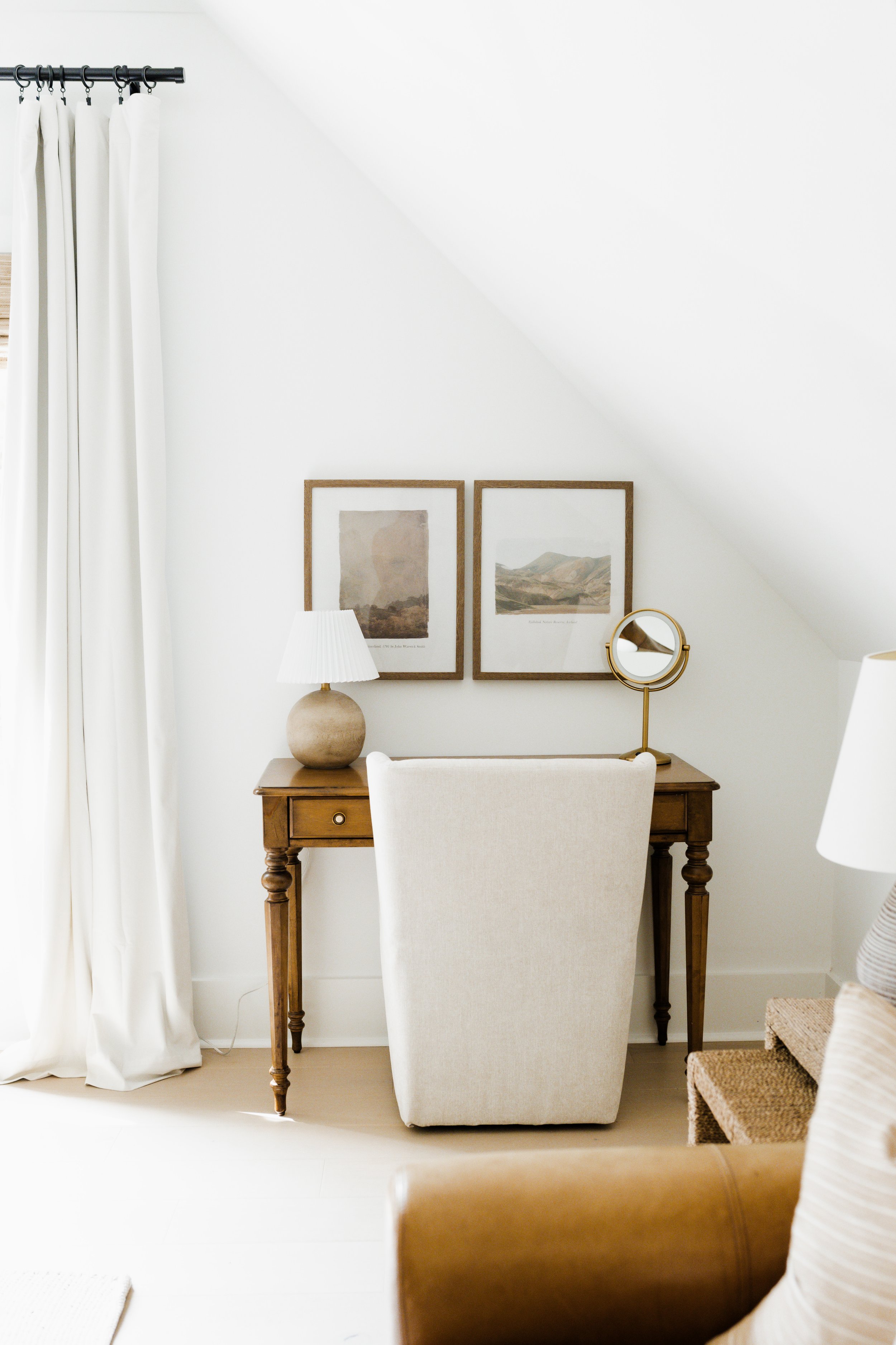 guest room sitting area desk with makeup mirror and neutral artwork