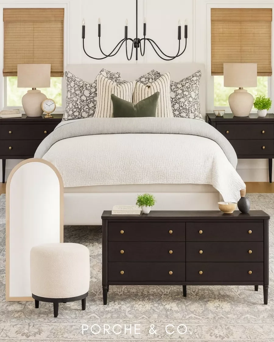 Styled bedroom with dark wood furniture, neutral bright cream bed with patterns and black chandelier
