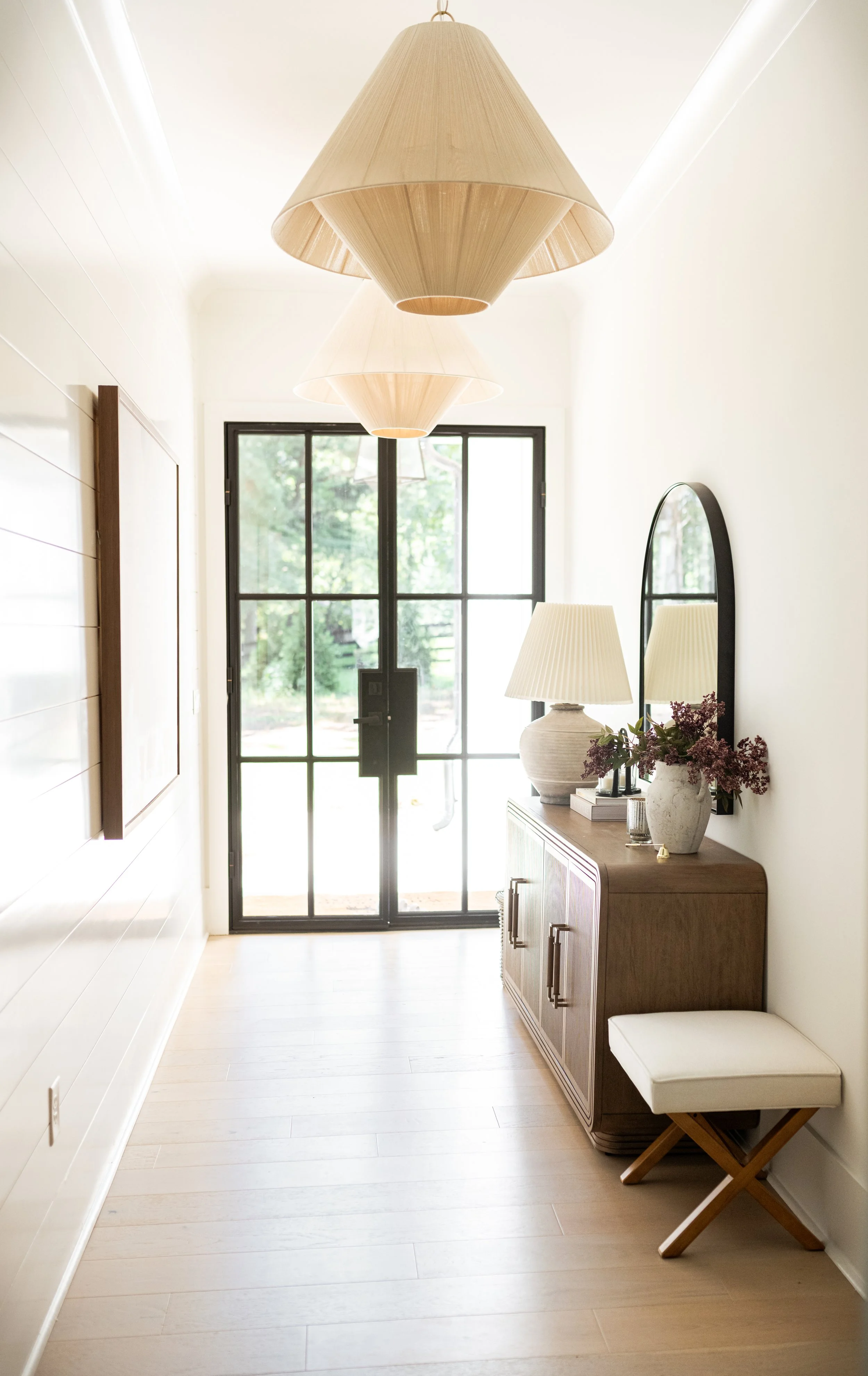 entry way with beautiful natural light and woven light with table, mirror, lamp, and stool