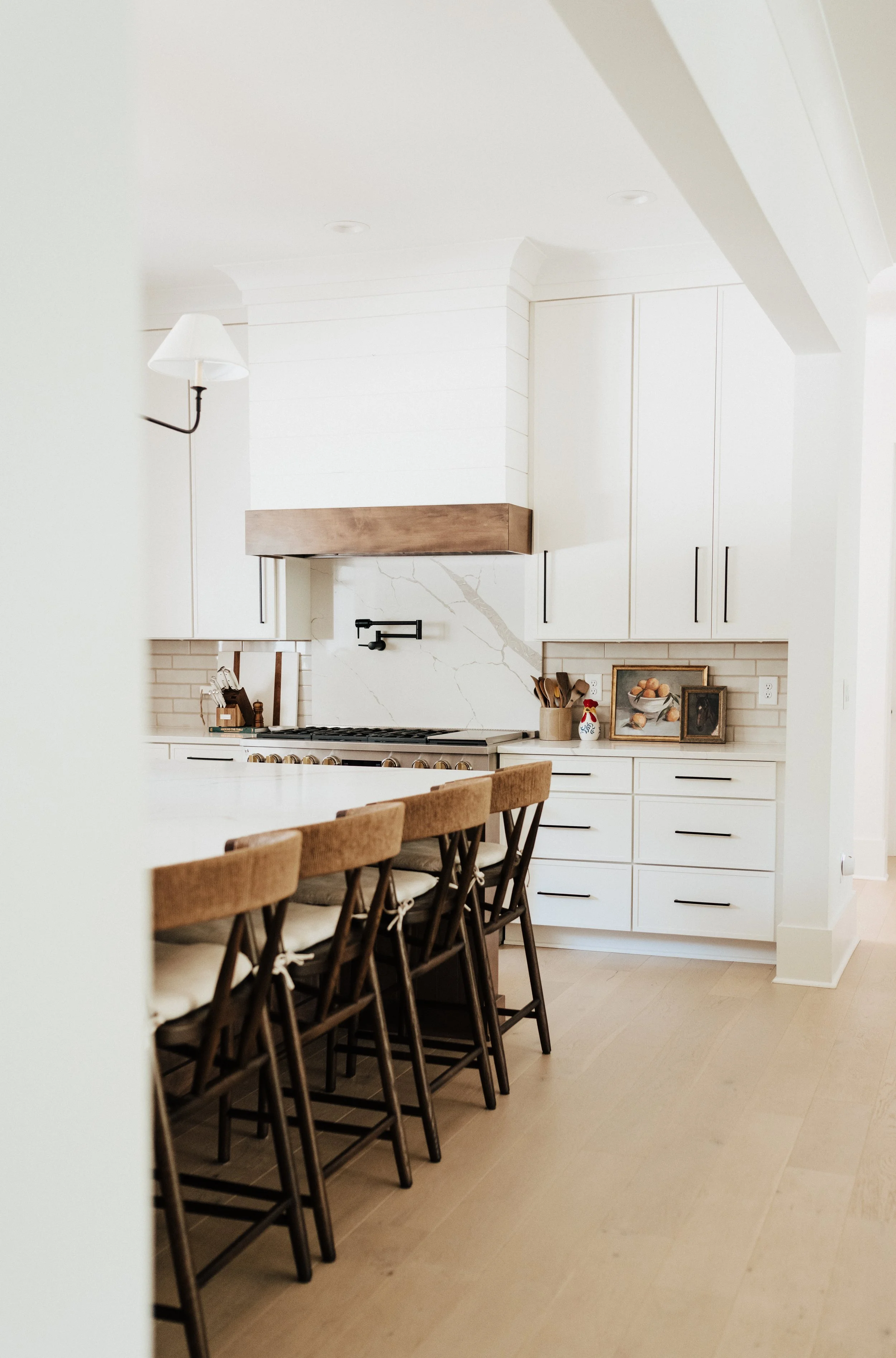 white kitchen with counter stools and black pot filler over stove