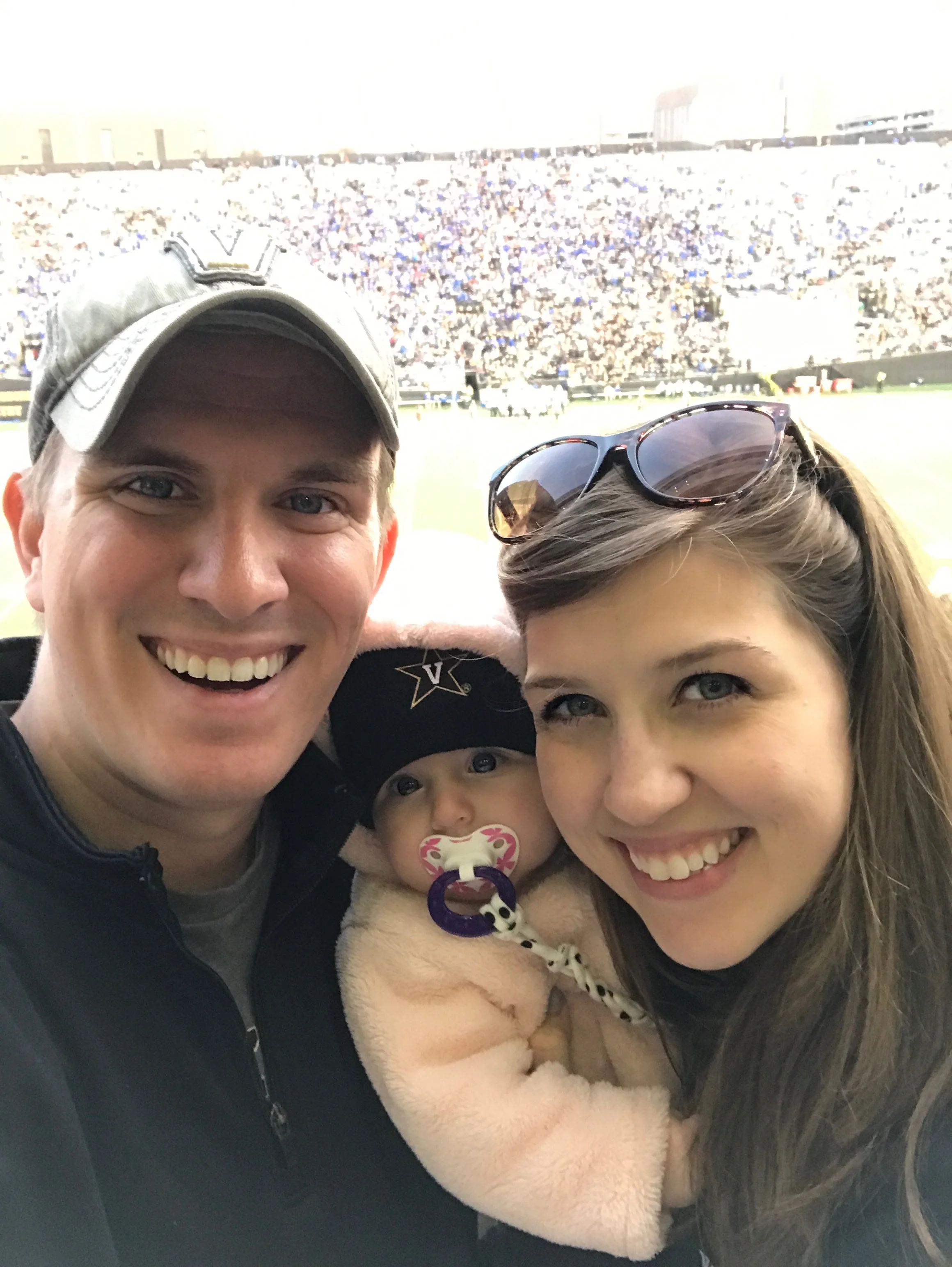Nick, Lauren, and their daughter watch a Vandy football game.
