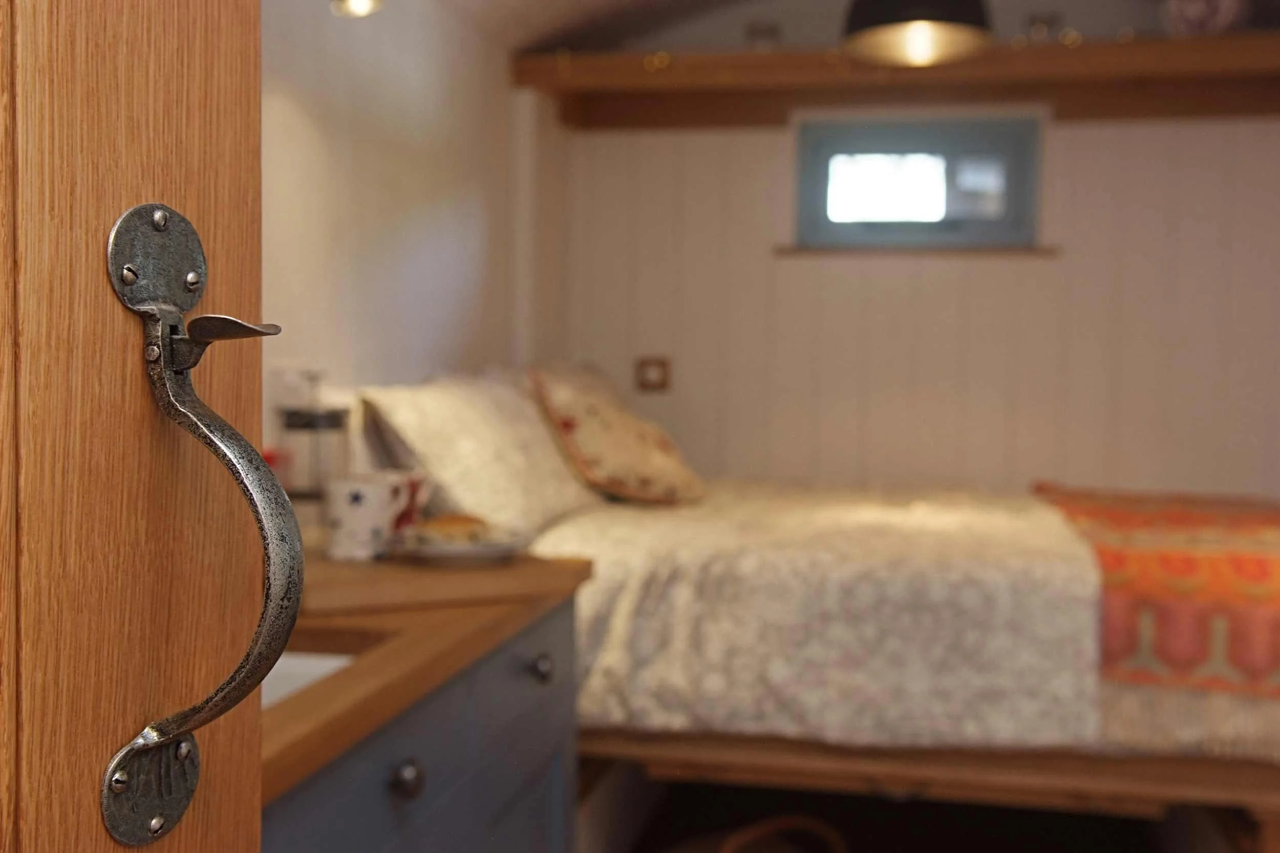 Interior of Shepherds Hut showing the pull down double bed, hand built door and hand forged iron door latches