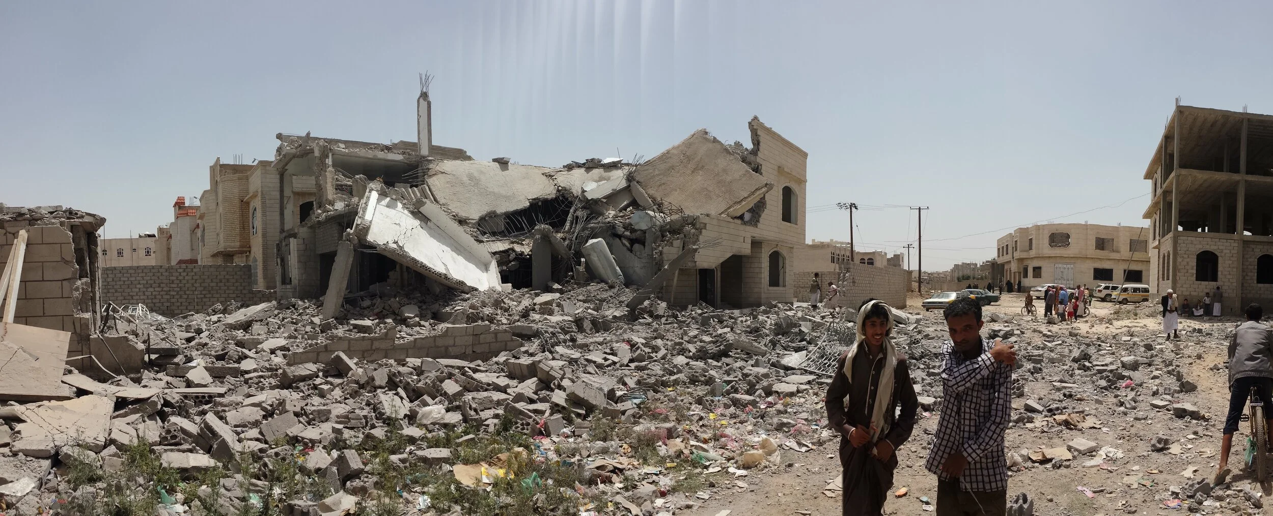 Yemenis stand next to a house destroyed by bombardment in Sana’a, 2016.