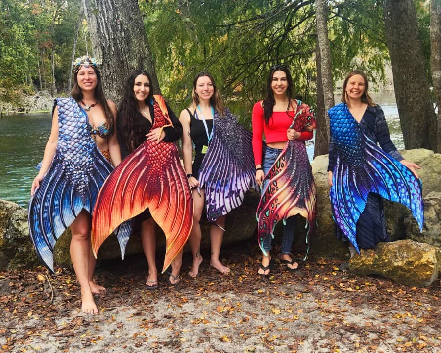 Mermaids holding beautiful Sereia Guardia mermaid tails at Spring Splash 2025 at Ginnie Springs.