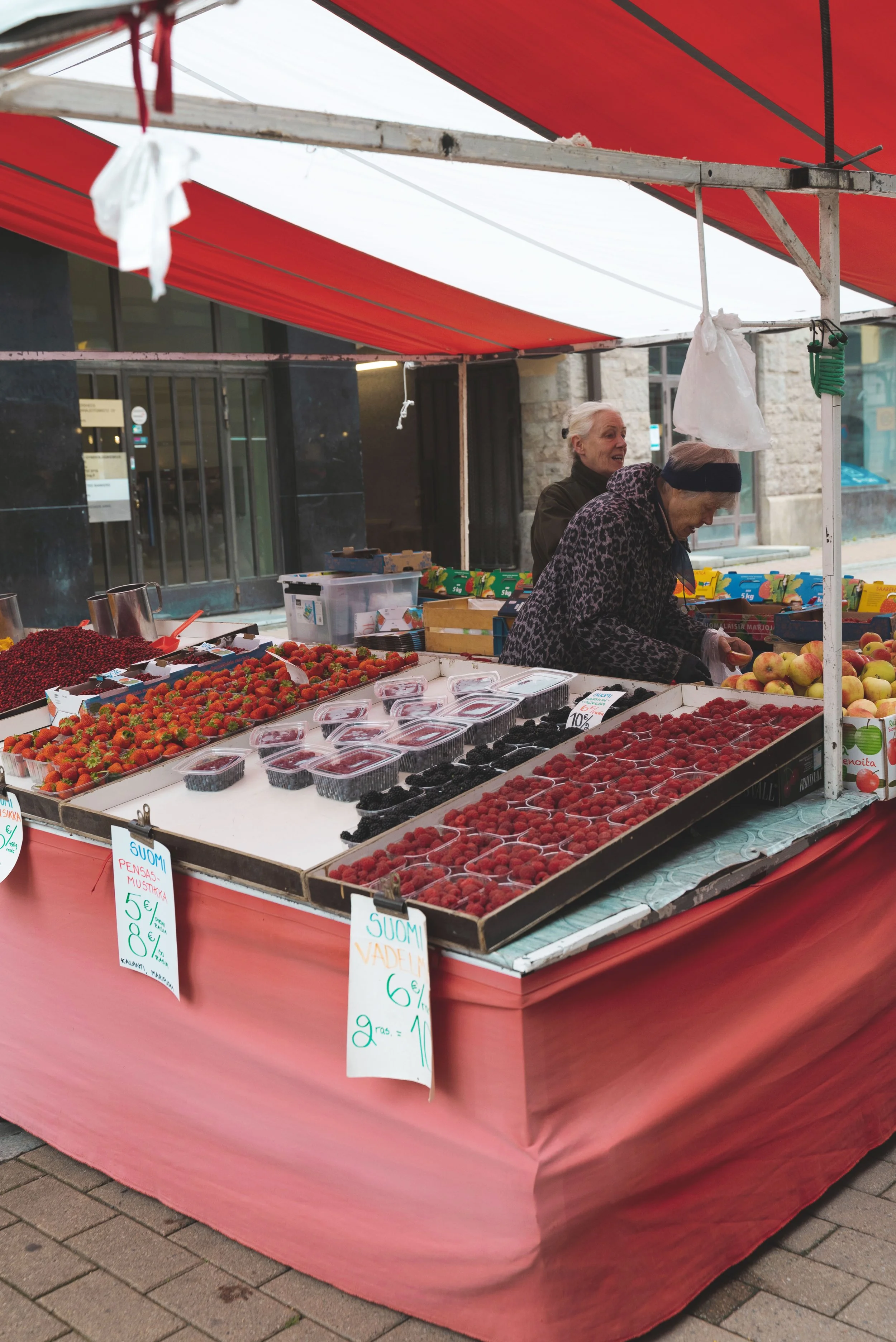 two women selling berries at a market in tampere finland
