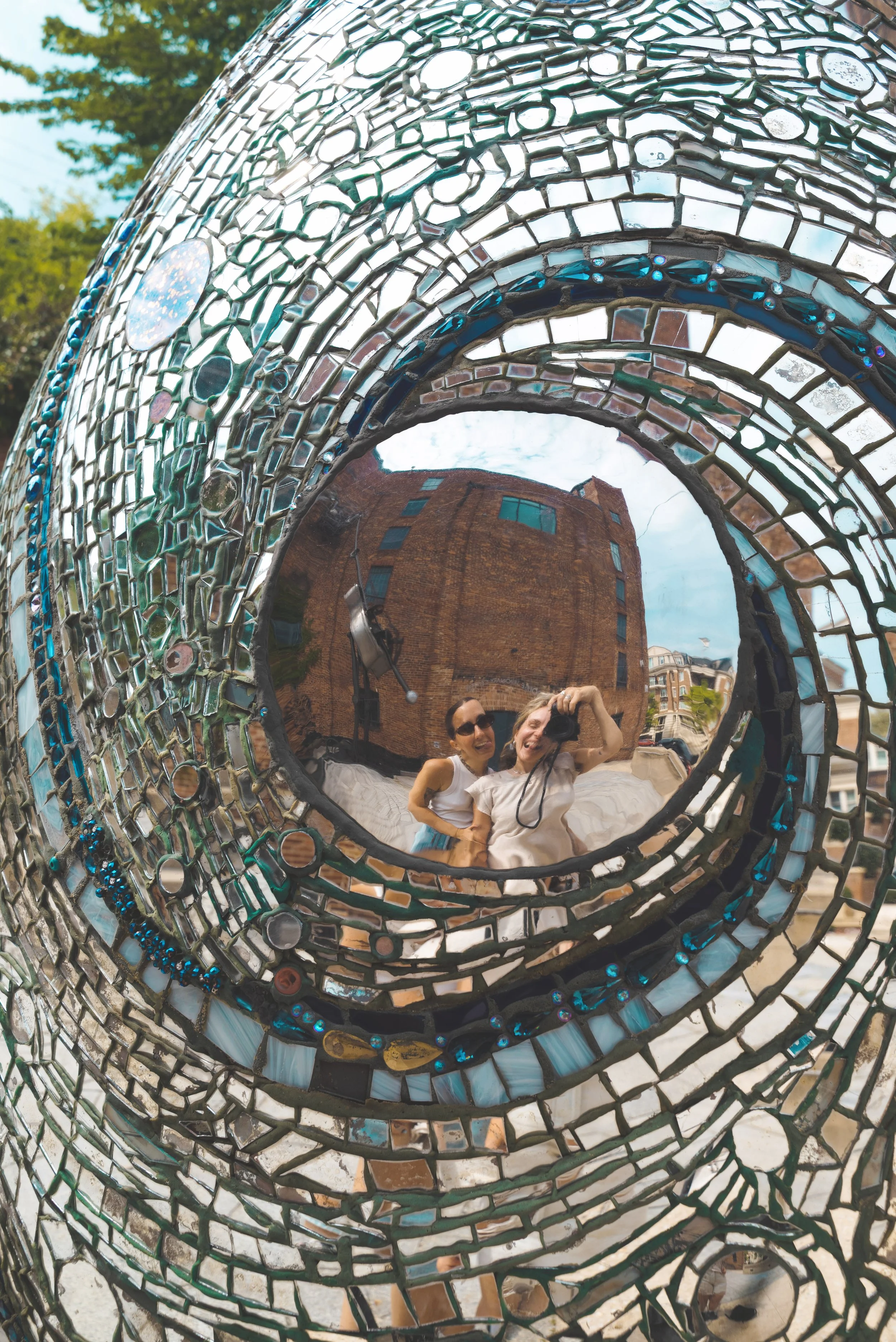 two girls taking a picture in the mirror of the mosic at the american visionary art museum baltimore